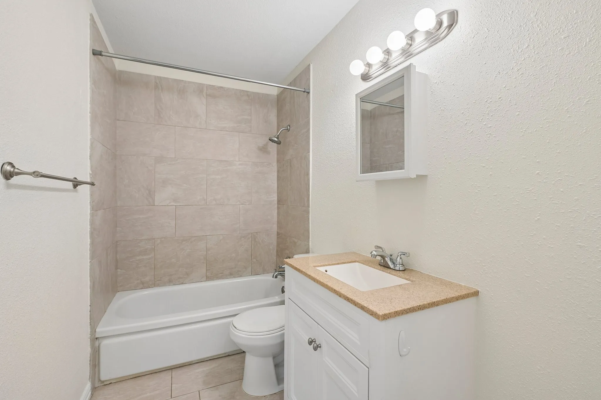 Bathroom featuring a white vanity with a light-toned countertop, a mounted medicine cabinet, and a tiled shower/tub combination