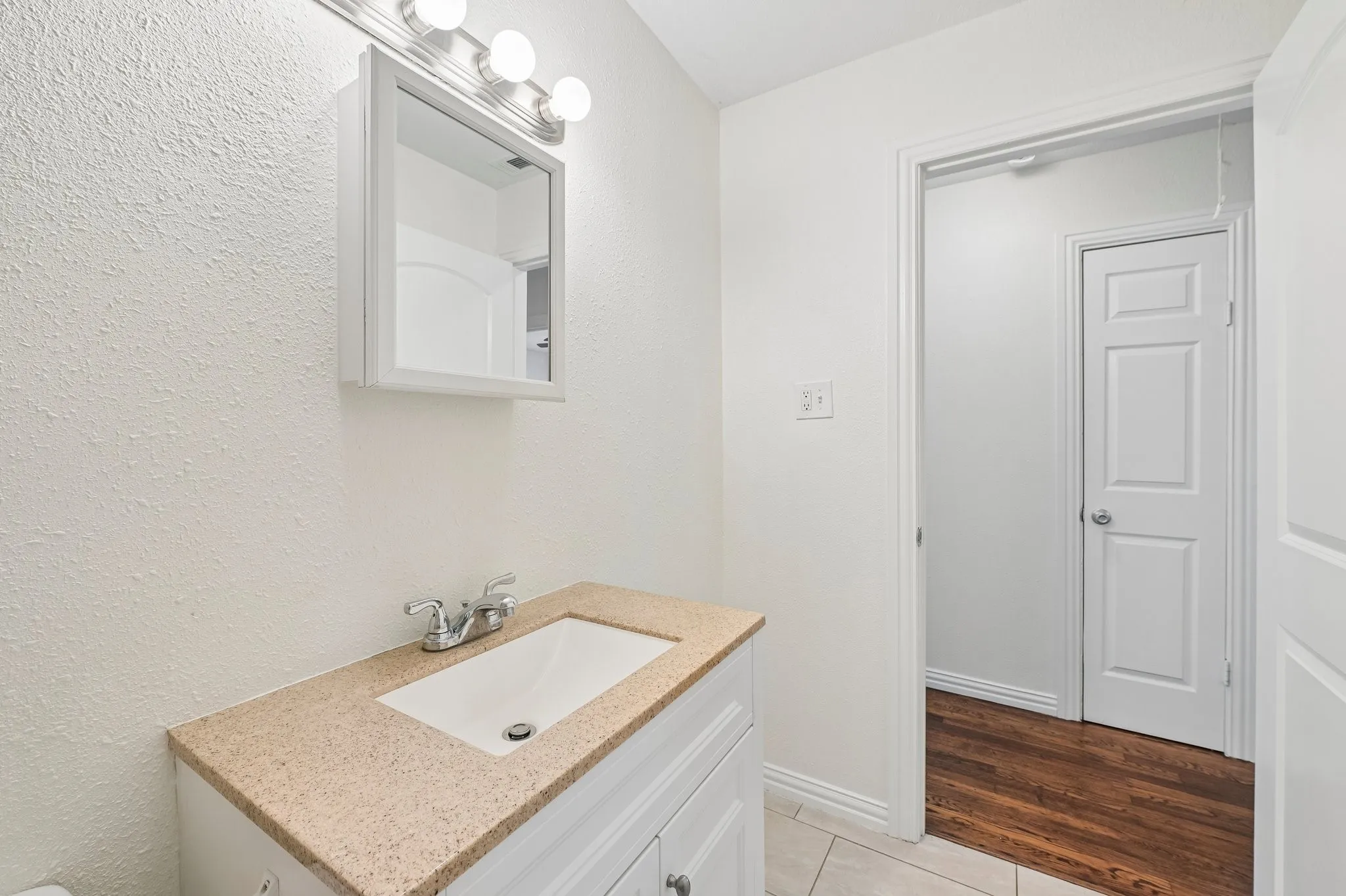 White shaker vanity with integrated sink, patterned countertop, and chrome faucet