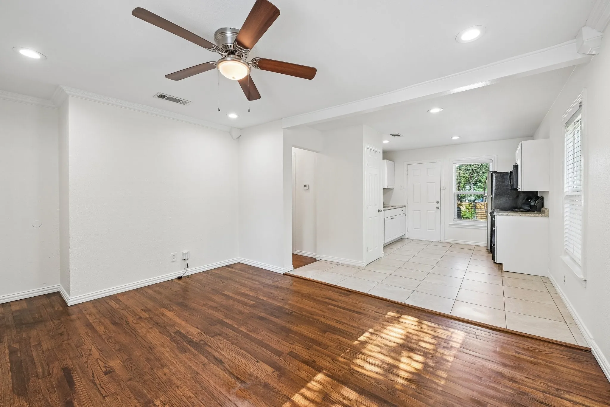 Wood-finish flooring, recessed lighting, ceiling fan, white cabinetry, and tile flooring