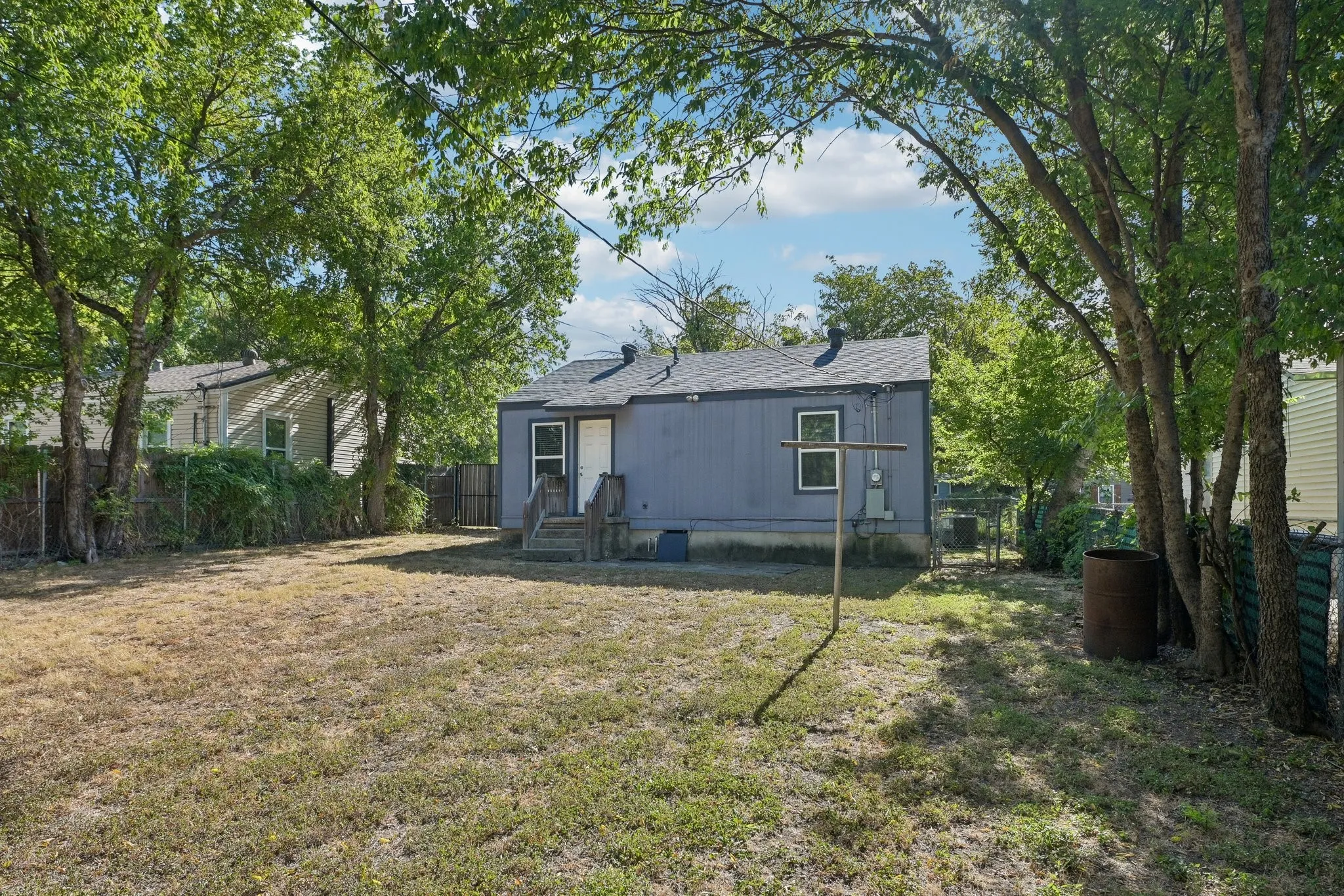 Spacious backyard with mature perimeter trees and a chain-link fence