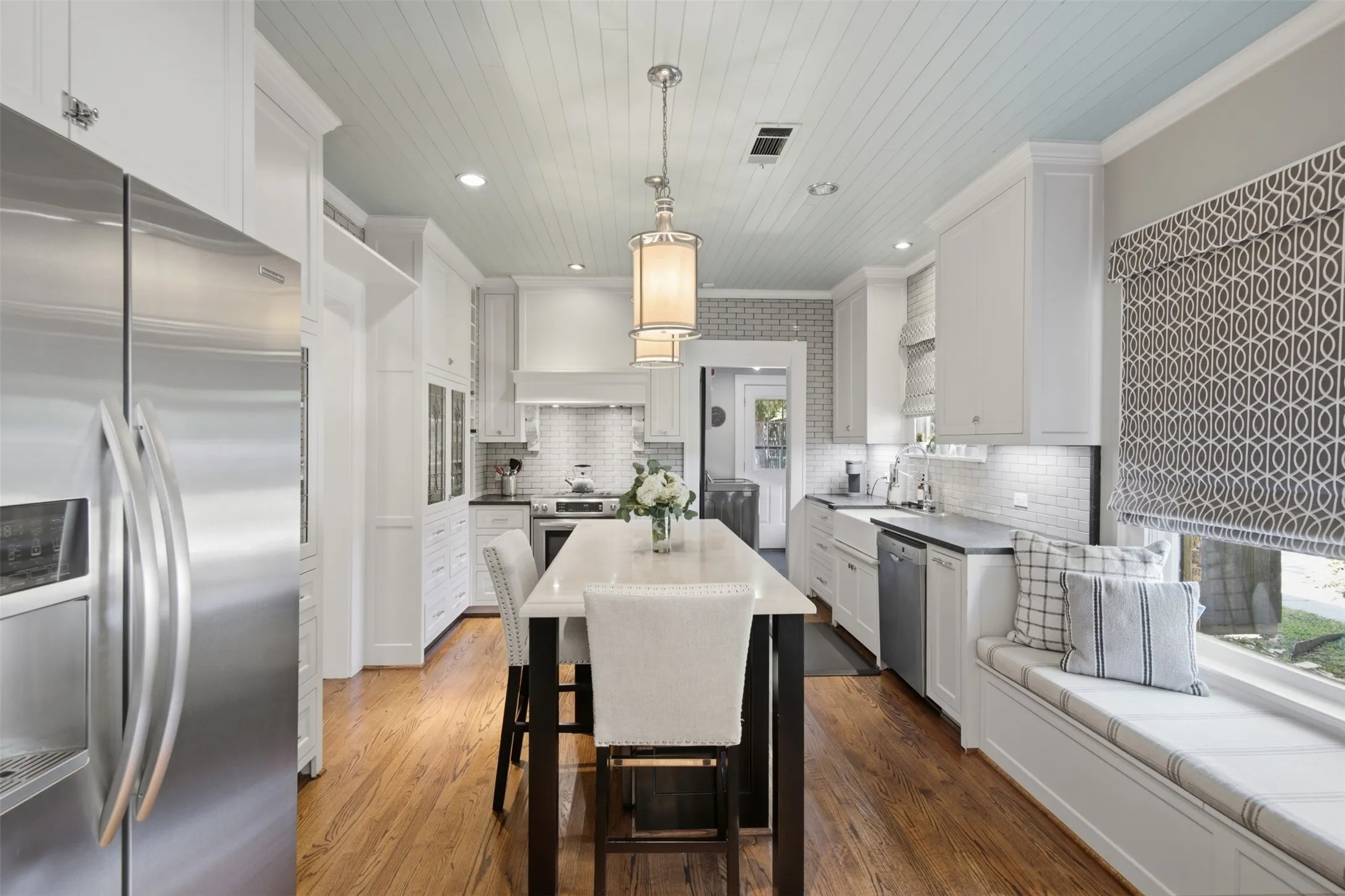 Kitchen featuring a central island, stainless steel appliances, a window bench seat, and wood-finish flooring