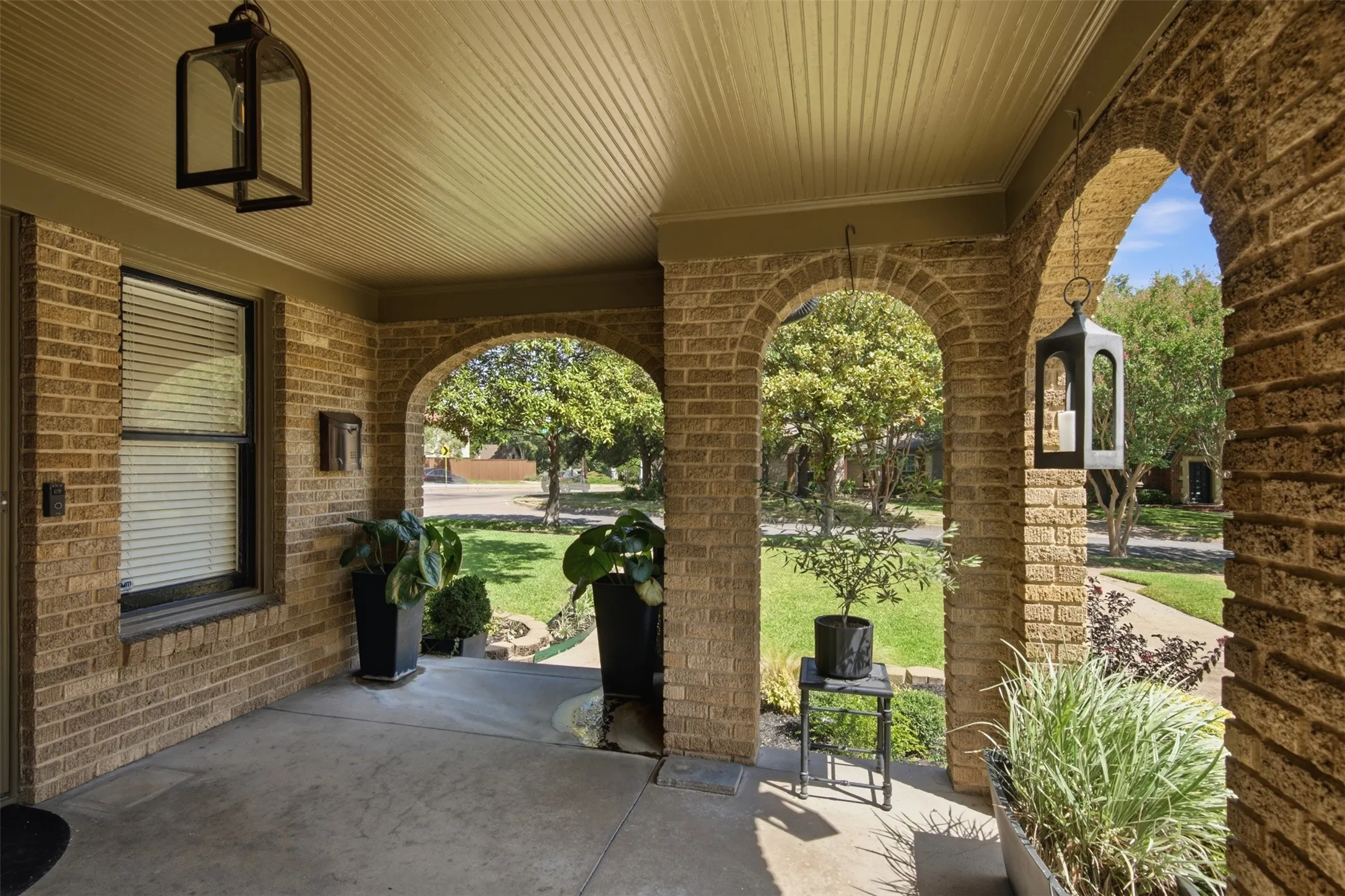Brick exterior facade with multiple archways, concrete flooring, and a paneled ceiling. Front porch is an inviting place to enjoy the evenings.