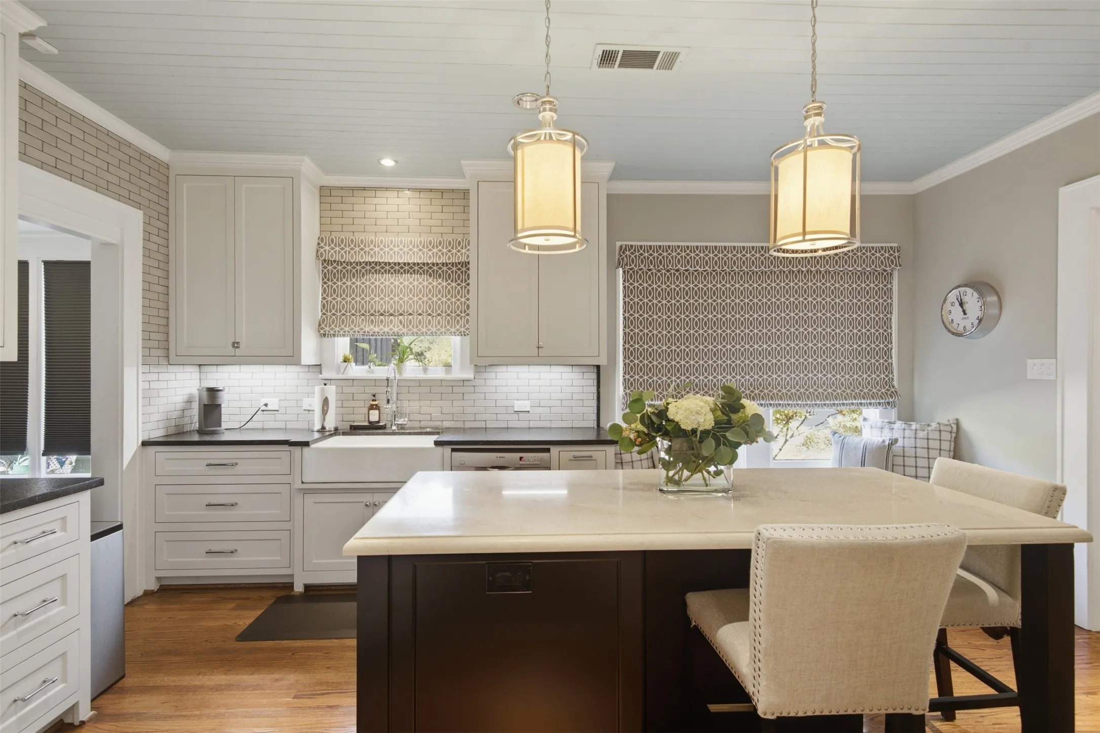 Kitchen featuring a central island with countertop seating, white shaker-style cabinetry, black countertops, and wood-finish flooring