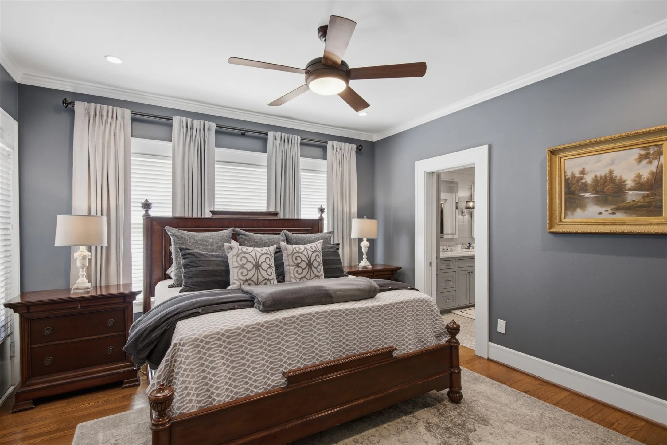 Wood-finish flooring, recessed lighting, crown molding, ceiling fan, and an en-suite bathroom featuring a double vanity