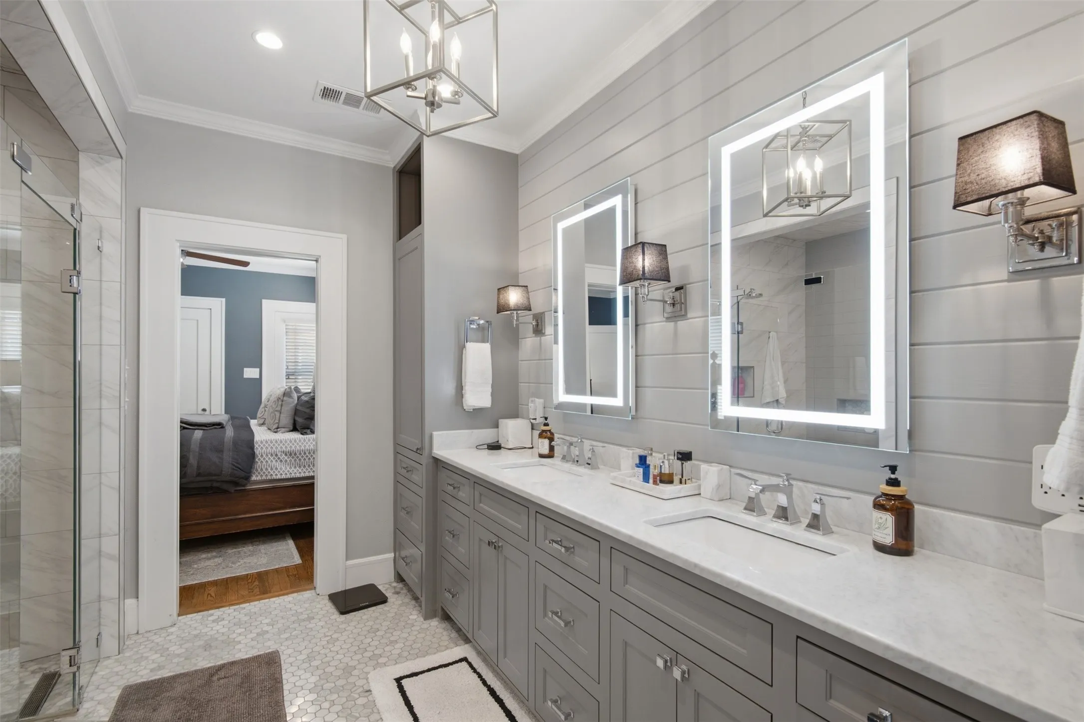 Dual vanity with integrated sinks and stone countertop, illuminated mirrors, and shiplap-style wall paneling