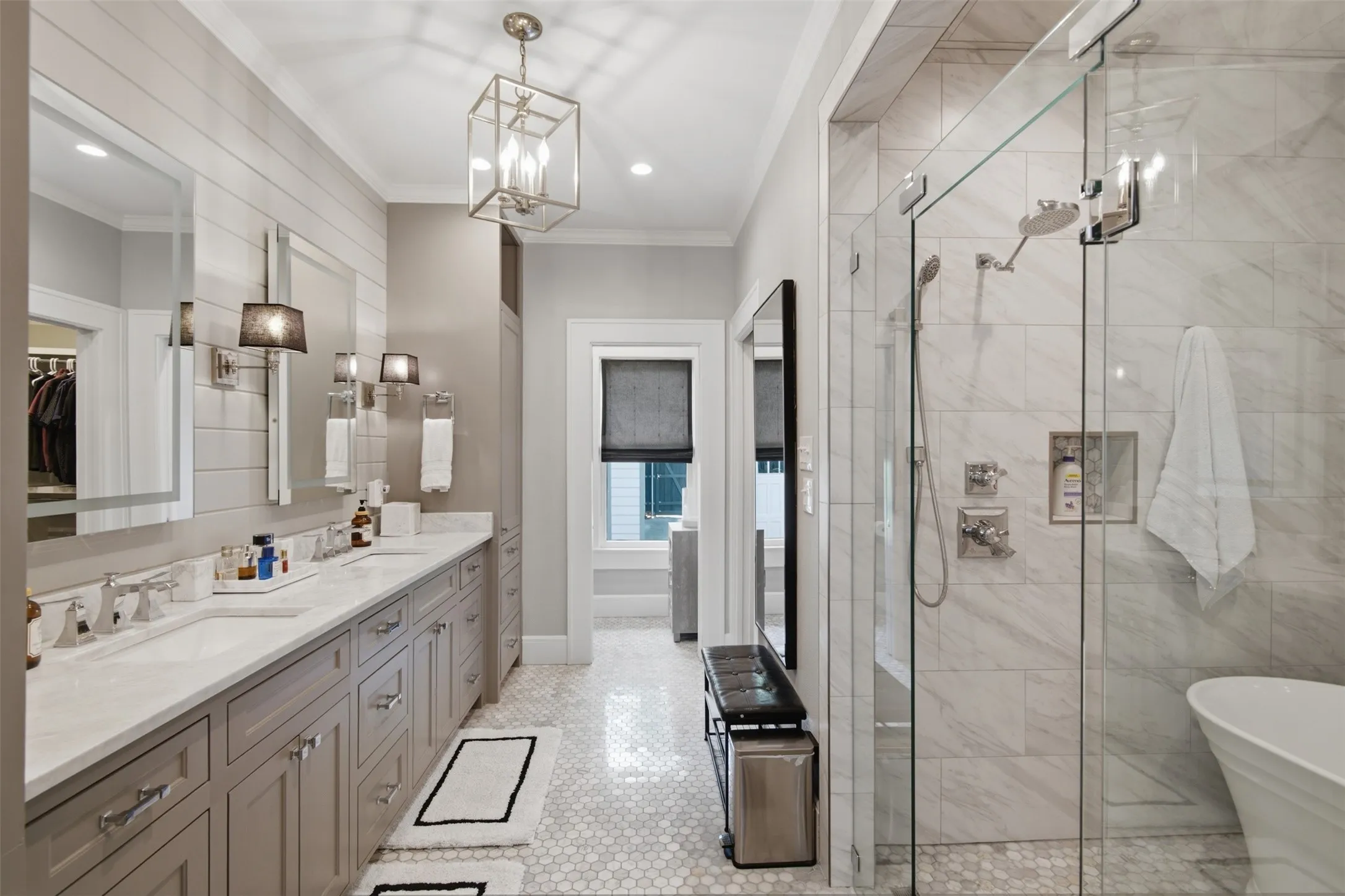 Dual vanity with white countertops, expansive walk-in shower with glass enclosure, freestanding soaking tub, and hexagonal floor tiling