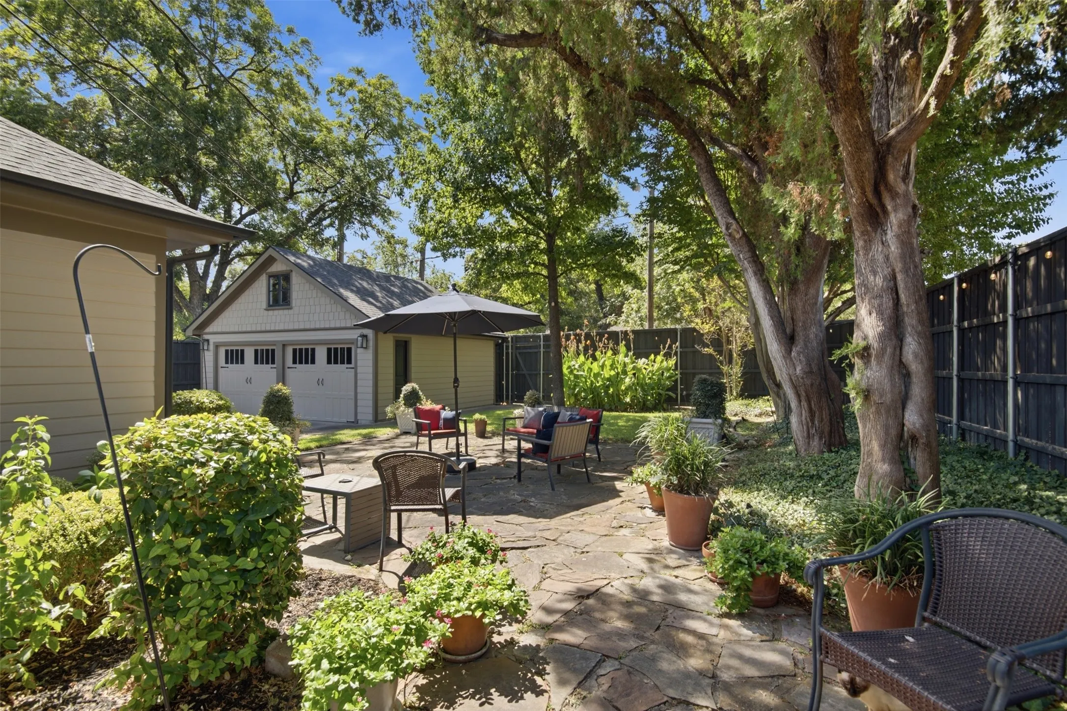 Expansive flagstone patio with a new detached two-car garage, mature trees, and privacy fencing