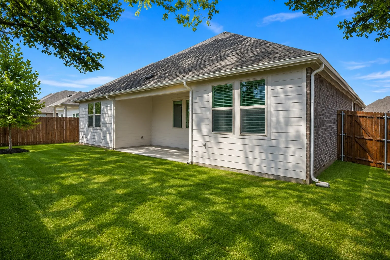 Expansive backyard with a covered patio, manicured lawn, and privacy fencing