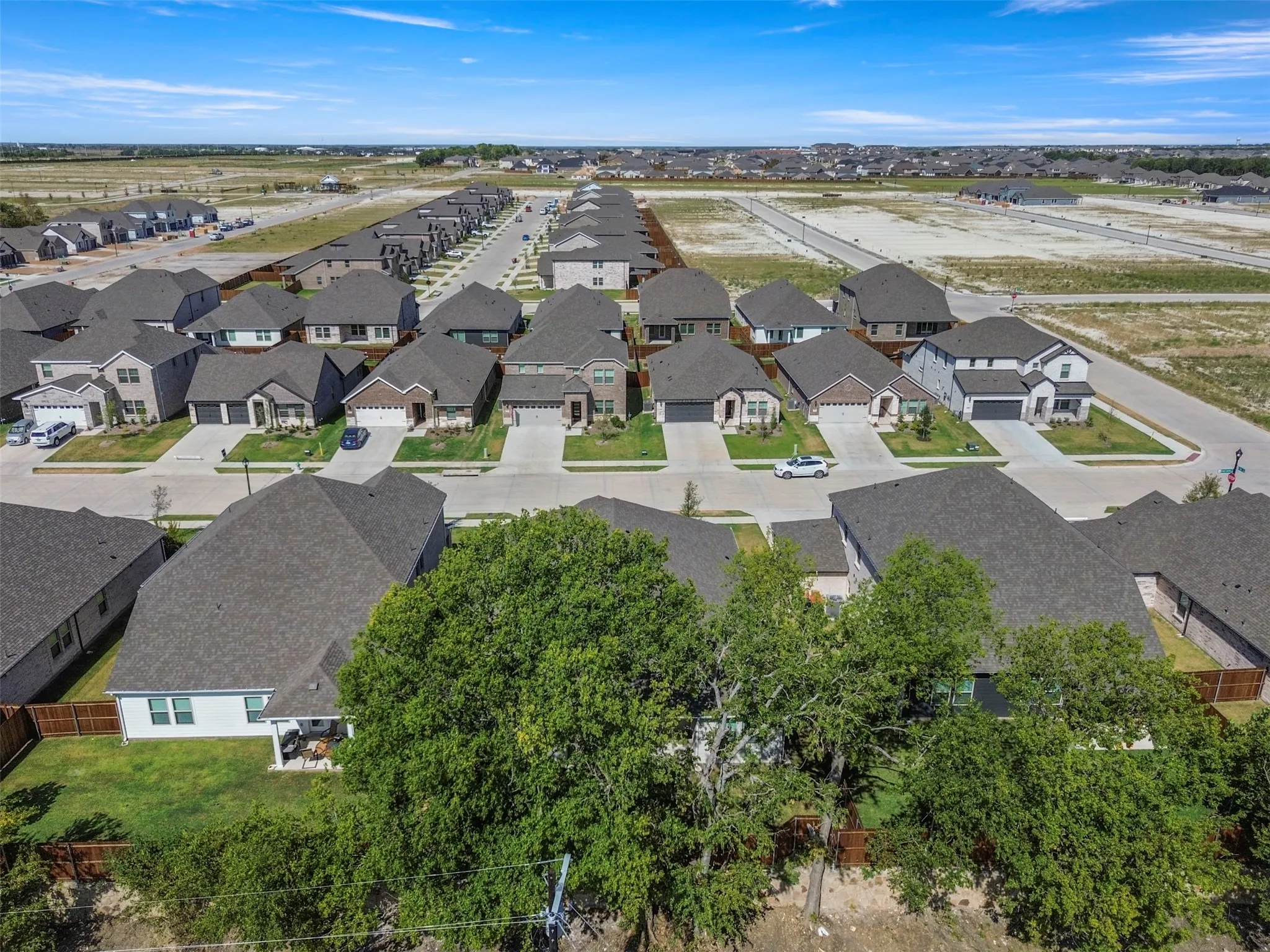 Neighborhood of single-story and two-story homes with dark asphalt shingle roofs and concrete driveways