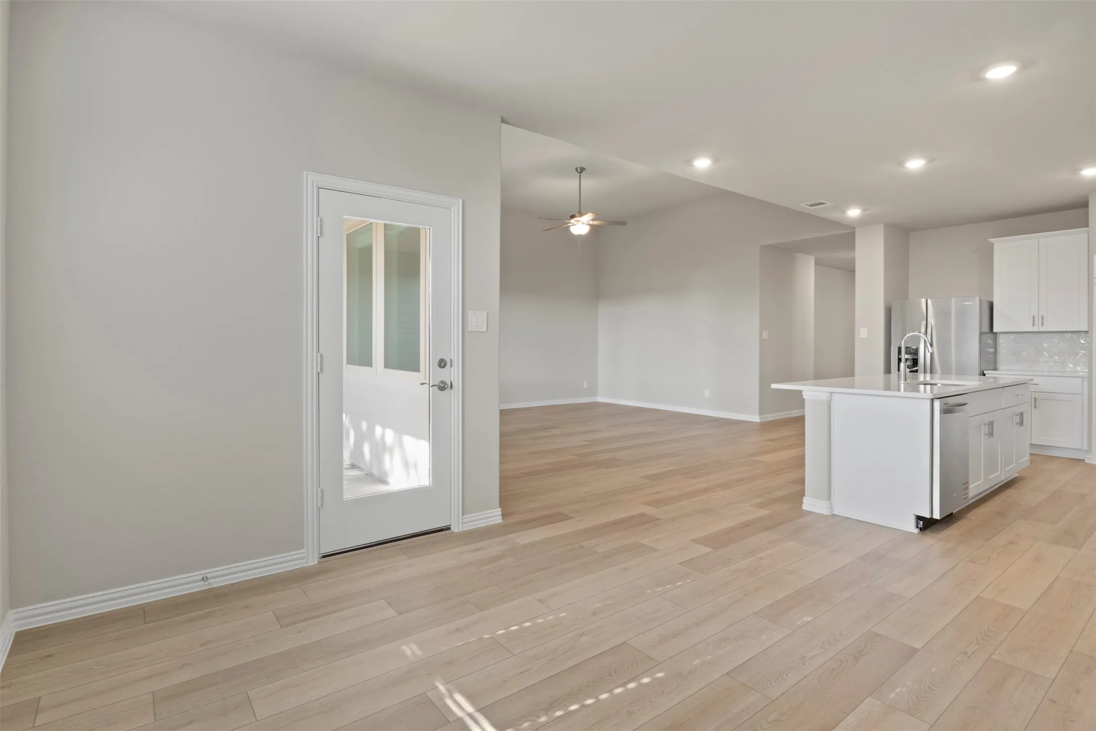 Open concept space featuring light wood-finish flooring, recessed lighting, and a ceiling fan