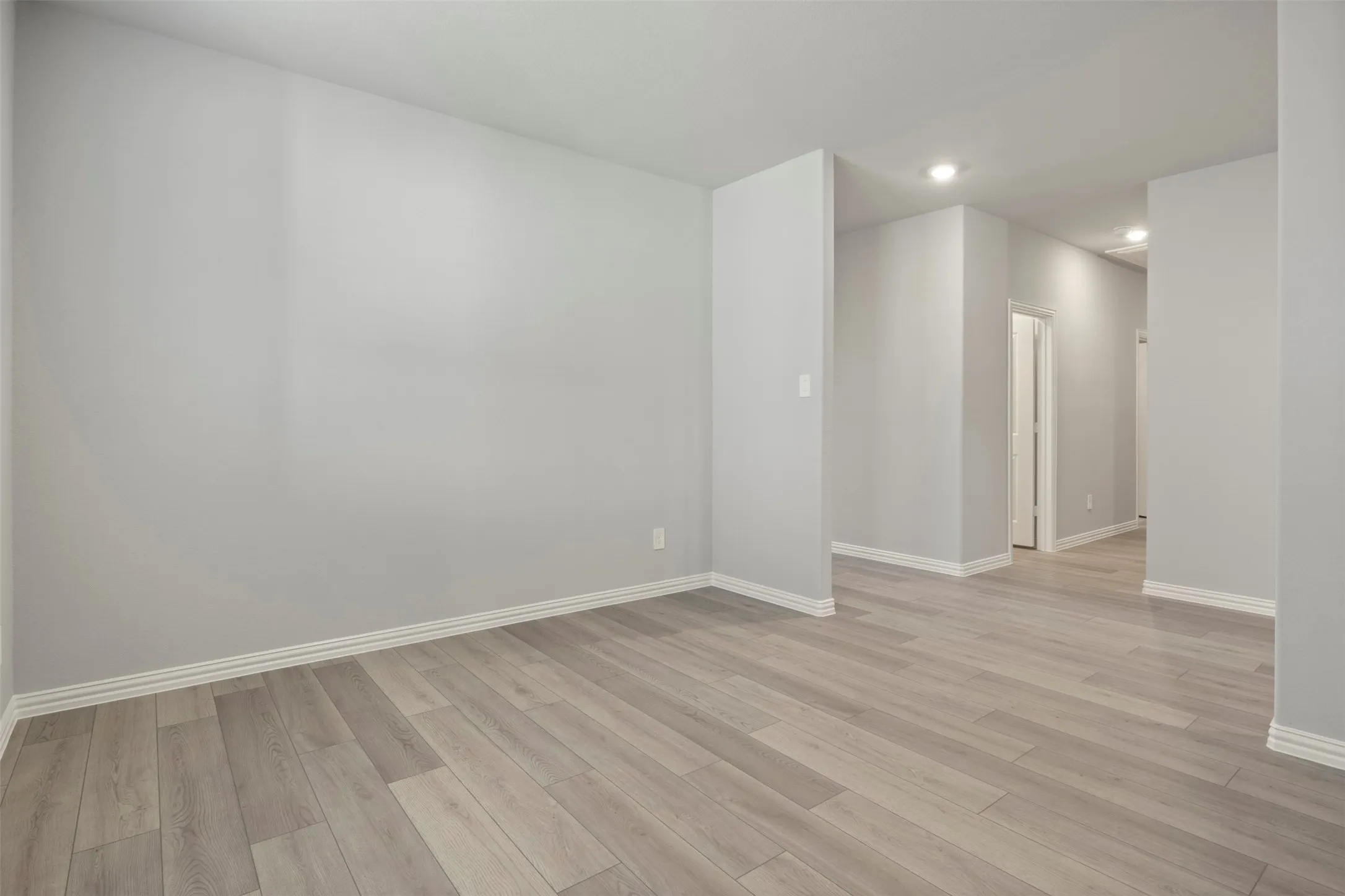 Expansive room featuring wood-finish flooring, recessed lighting, and light gray wall finishes