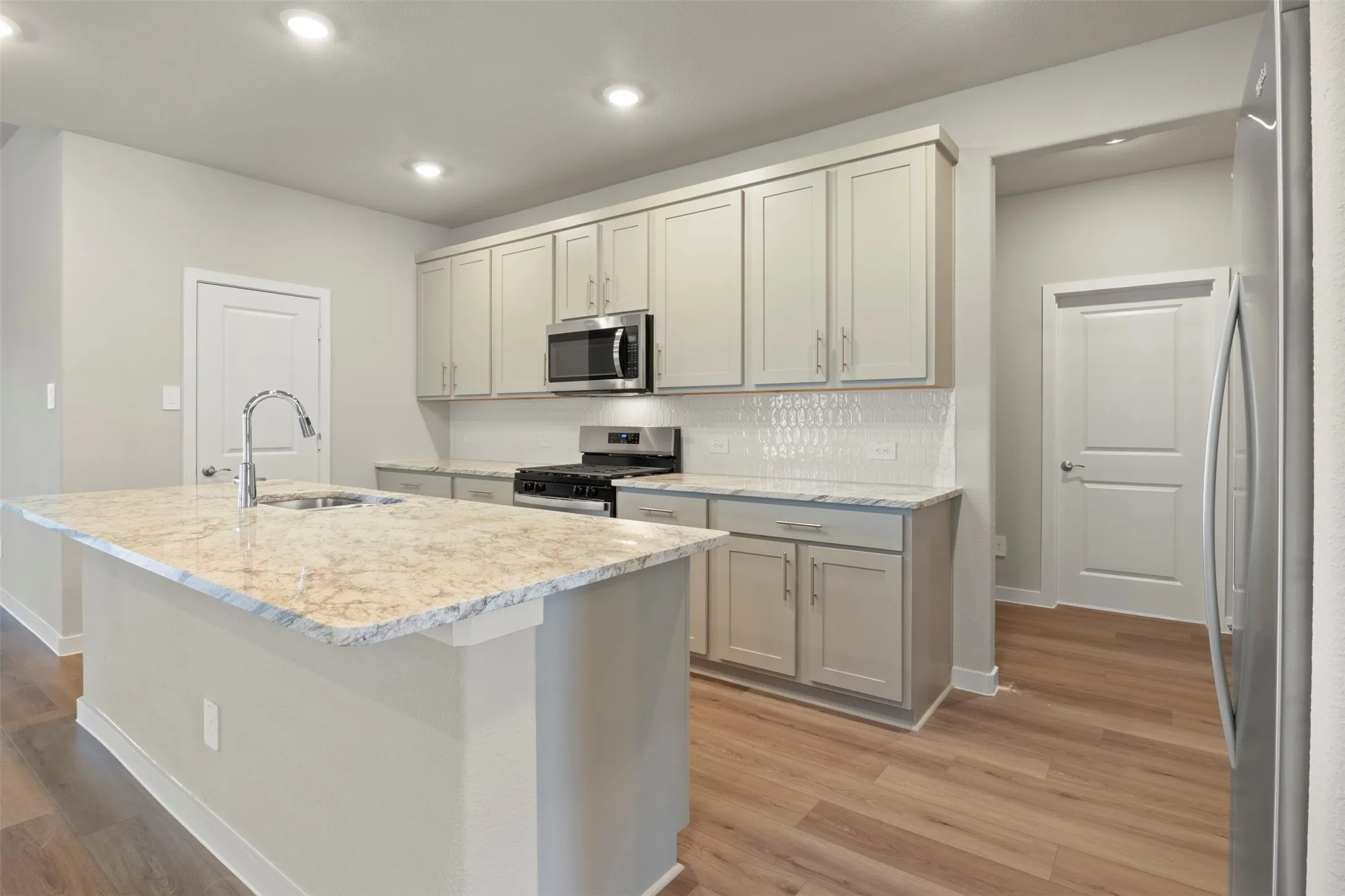Expansive kitchen island with a stone countertop, stainless steel sink, and a gooseneck faucet