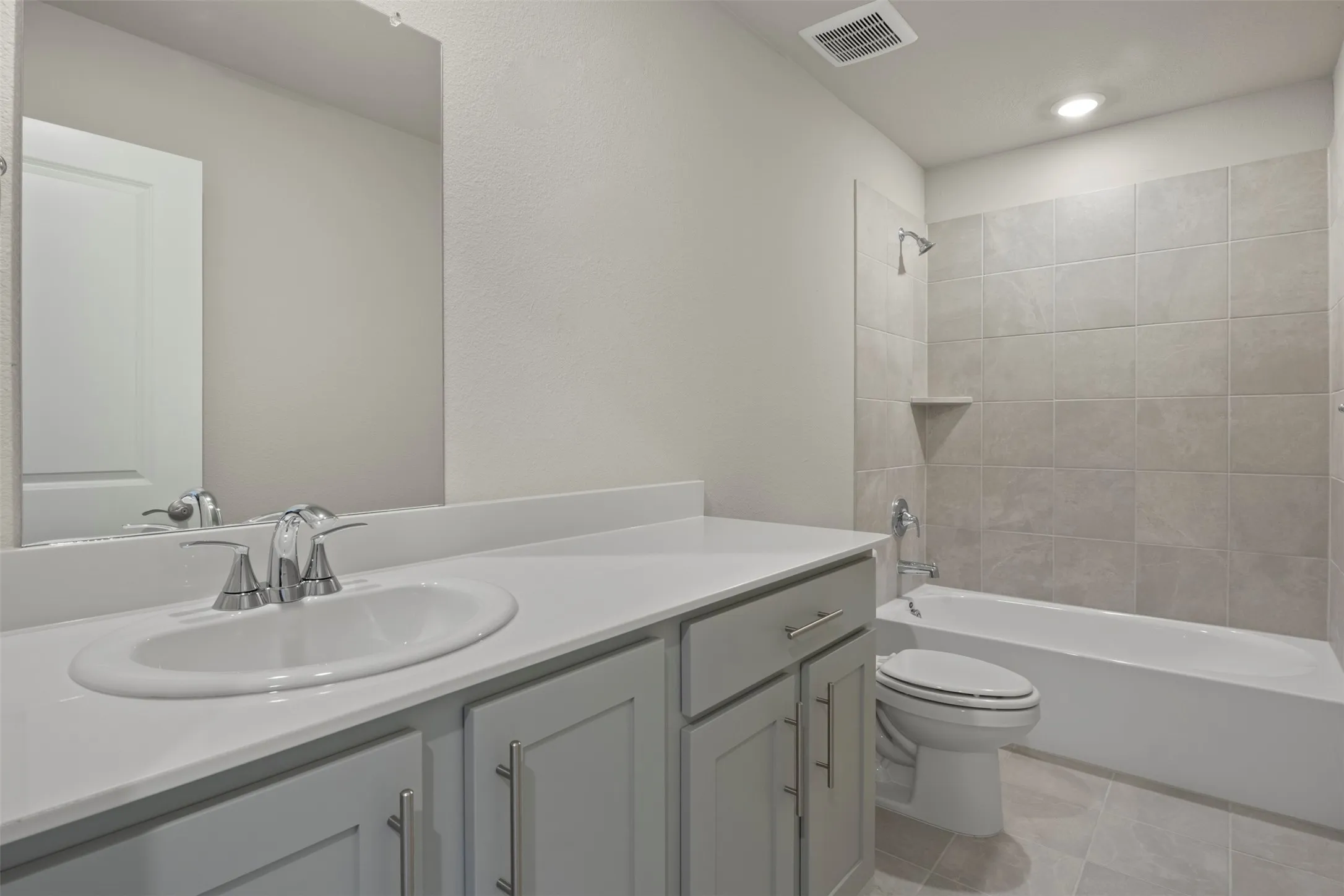 Vanity with an integrated sink, polished chrome faucet, gray cabinetry, and a full-width mirror