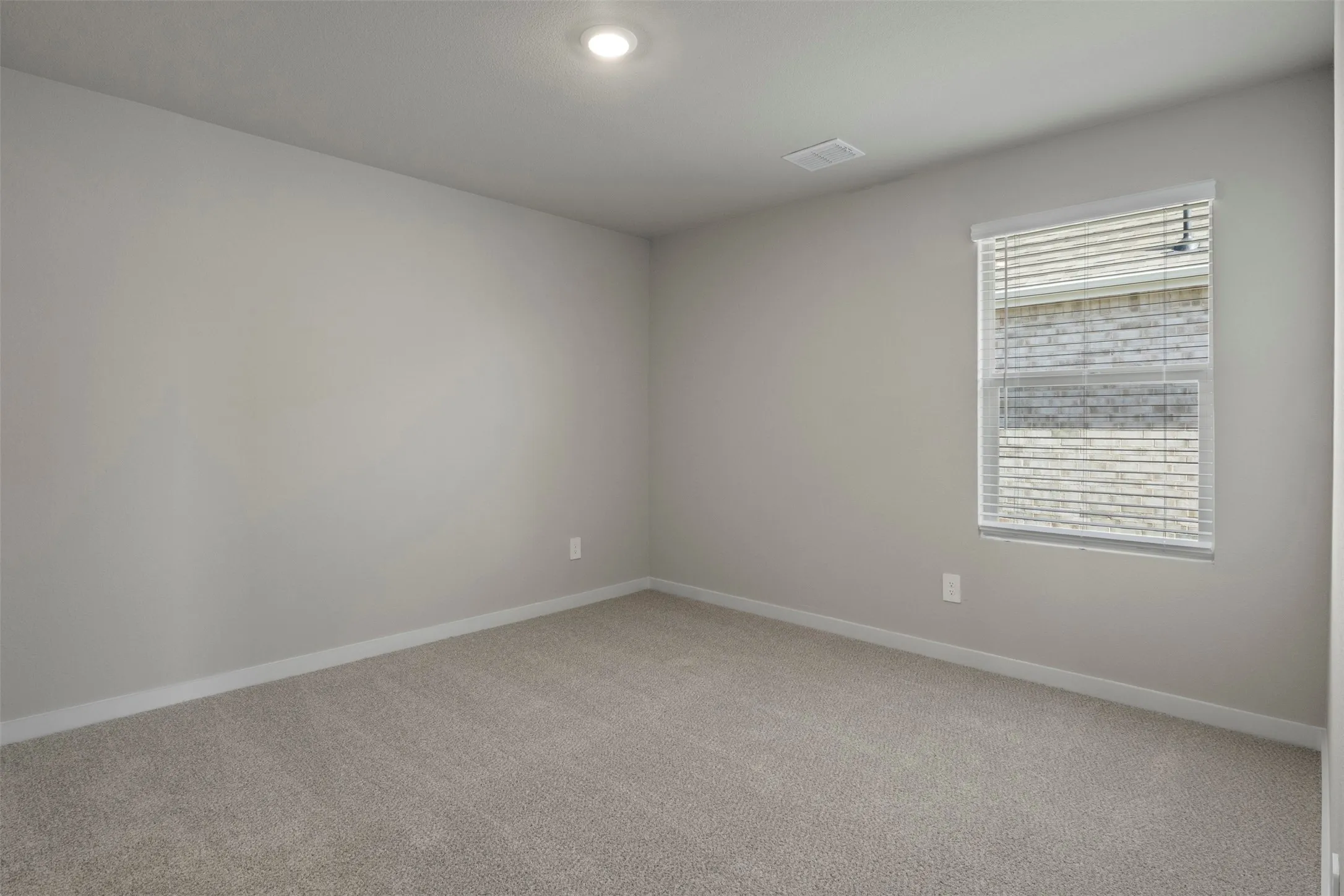 Recessed ceiling lighting, neutral-toned carpeting, light gray wall paint, and a window with blinds
