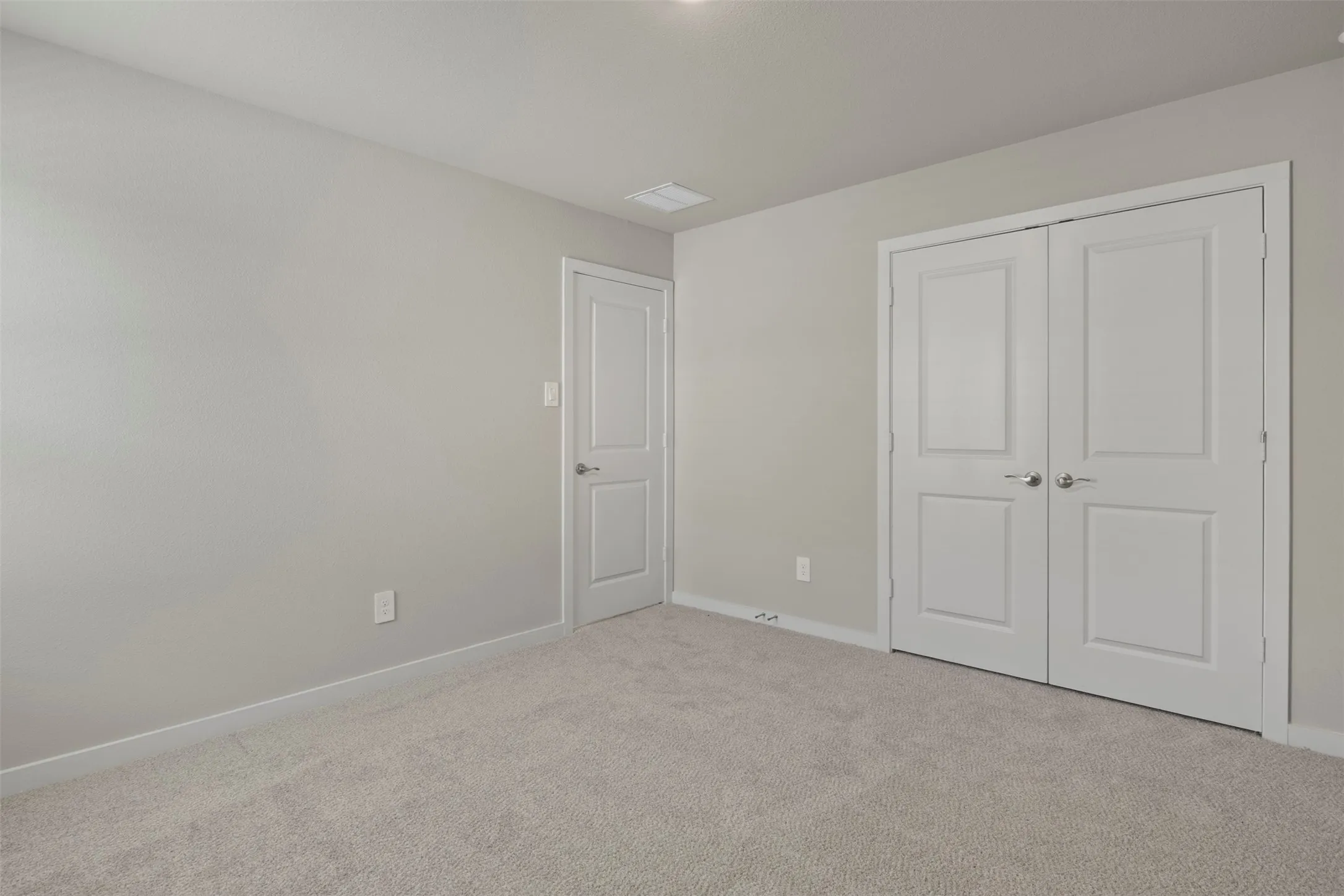 Neutral wall paint, light-colored carpeting, white trim, and white paneled doors