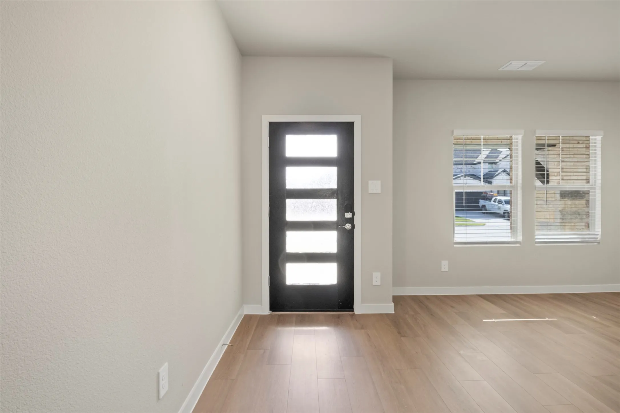Wood-finish flooring throughout, bright interior paint, and a modern entry door with frosted glass panels