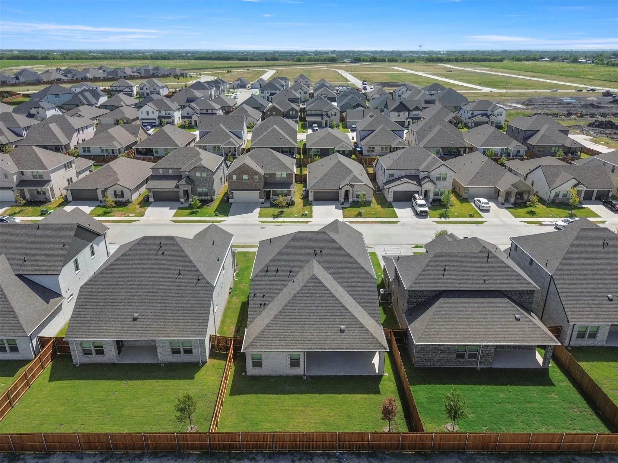 Aerial perspective showcasing a residential neighborhood with uniform rooflines and individual fenced backyards