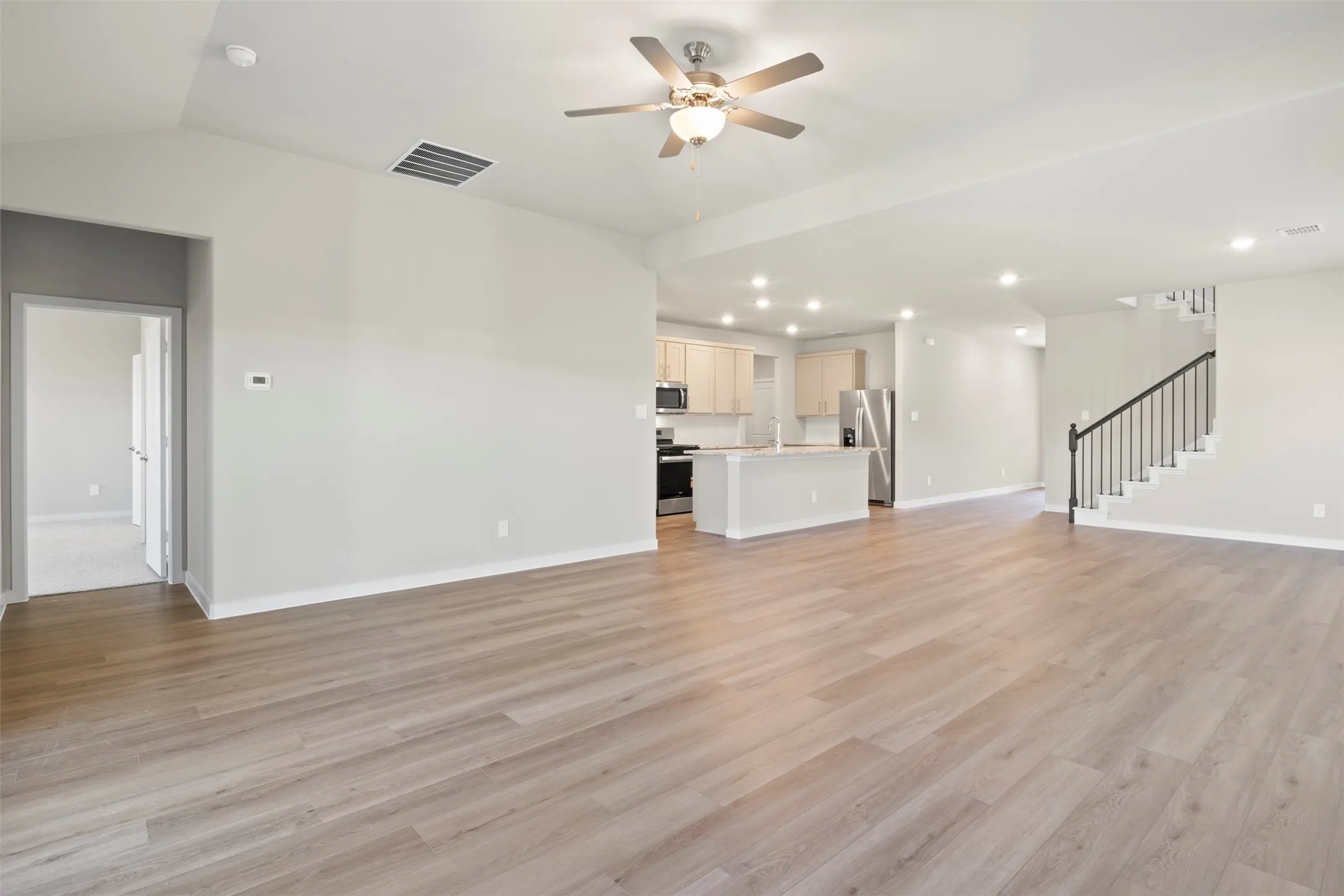Open concept living area with wood-finish flooring, recessed lighting, and a ceiling fan