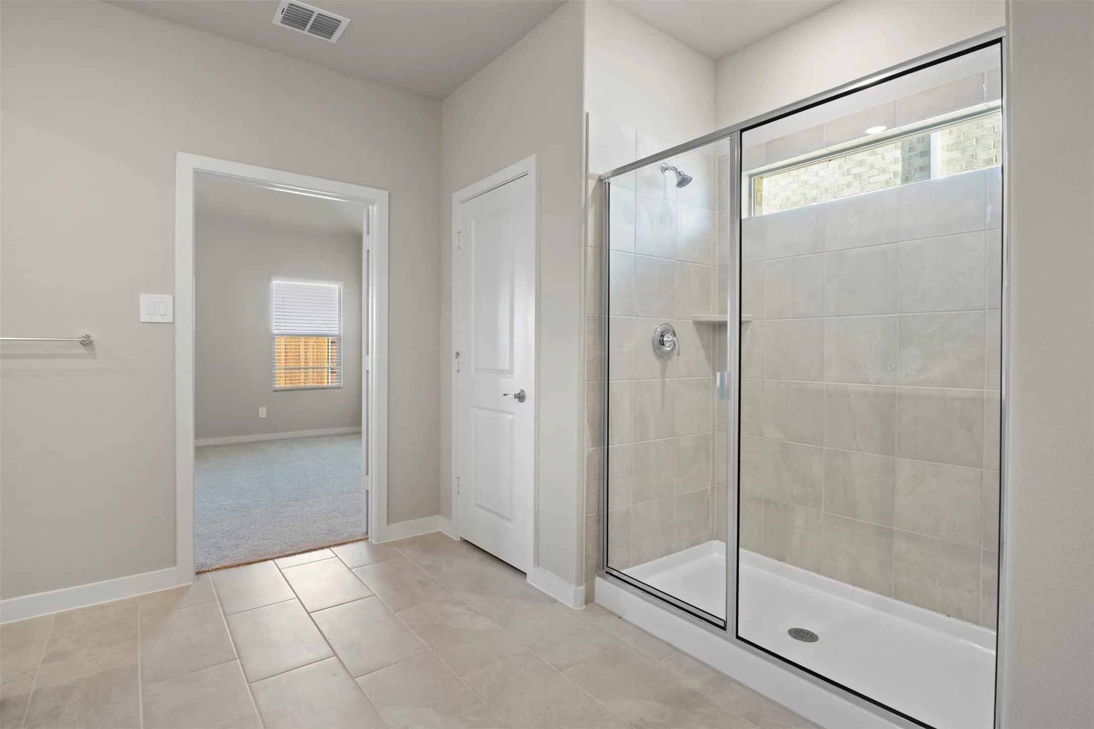 Walk-in shower with clear glass enclosure, tiled walls, and integrated shower niche