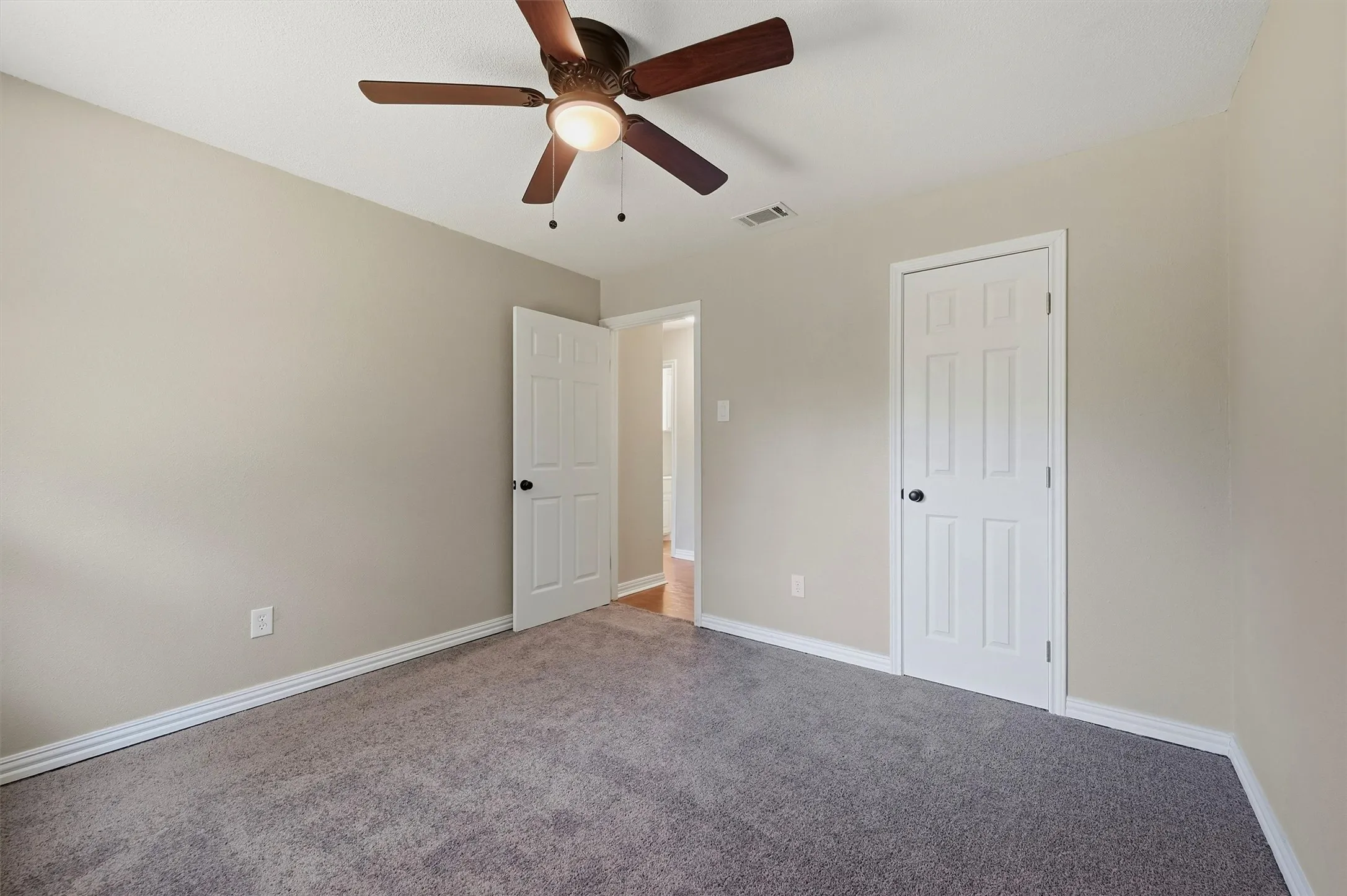Neutral wall paint with gray carpeting, white trim, and a ceiling fan