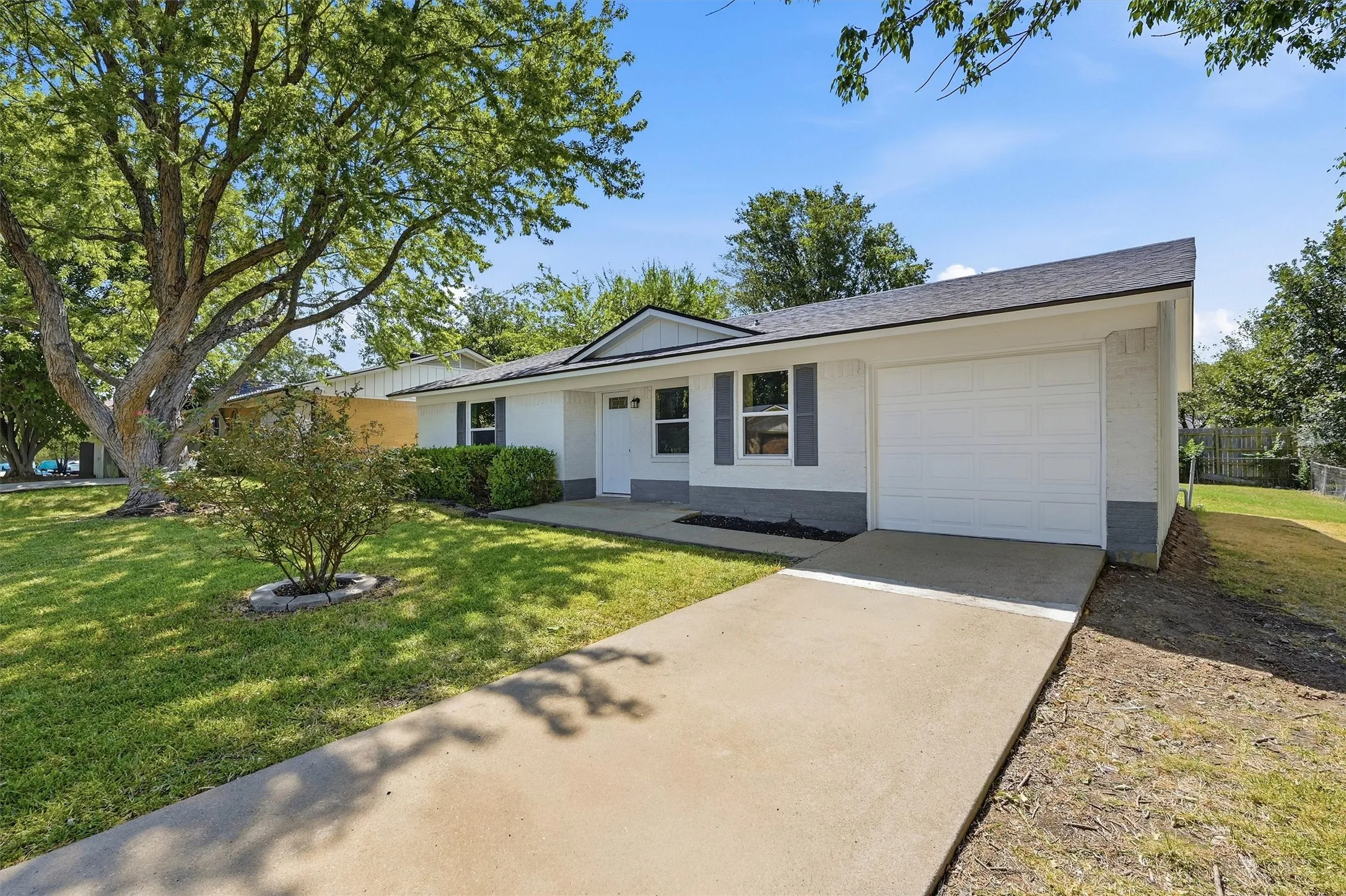 Single-story residence featuring a white exterior with gray accents, dark shutters, and a dark shingle roof