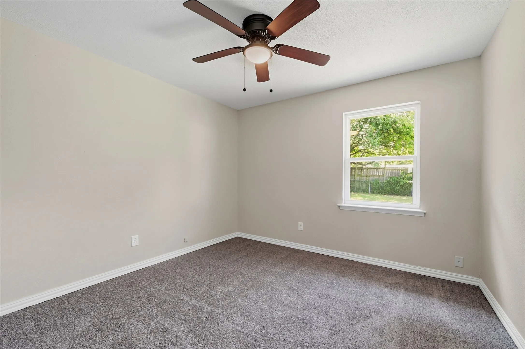 Neutral paint palette with carpeted flooring, a single window, white trim, and a ceiling fan with integrated lighting