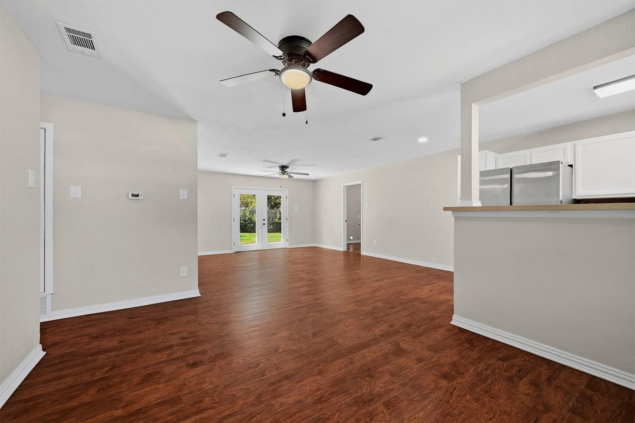 Expansive living area featuring rich wood-finish flooring, recessed lighting, and multiple ceiling fans