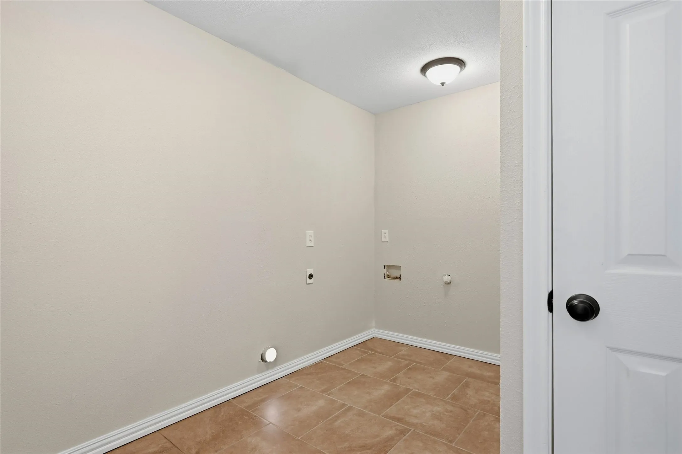 Ceramic tile flooring, neutral wall tones, recessed ceiling light, and white paneled door with black hardware