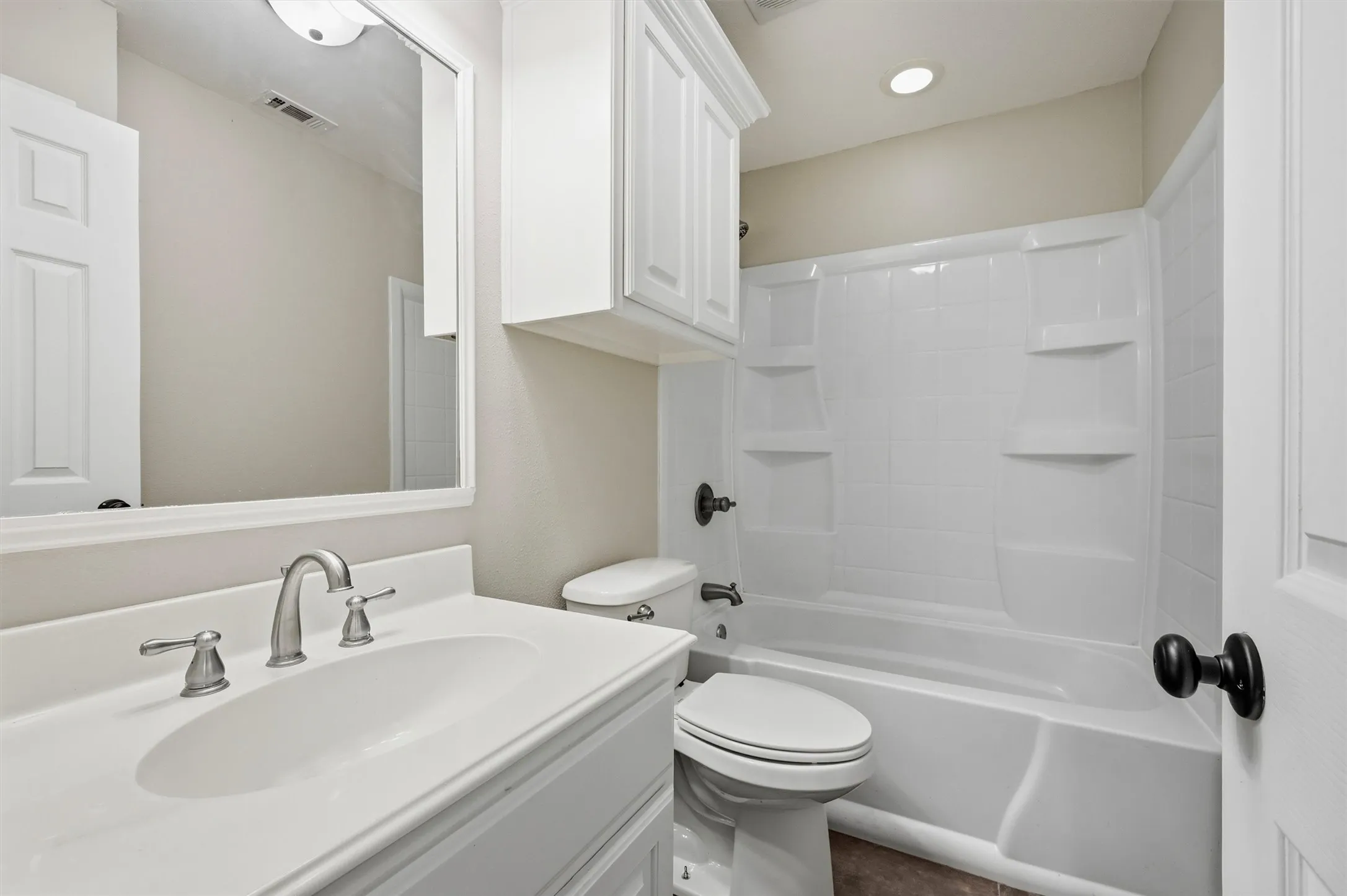 White vanity with integrated sink, brushed nickel faucet, wall-mounted mirror, and overhead lighting