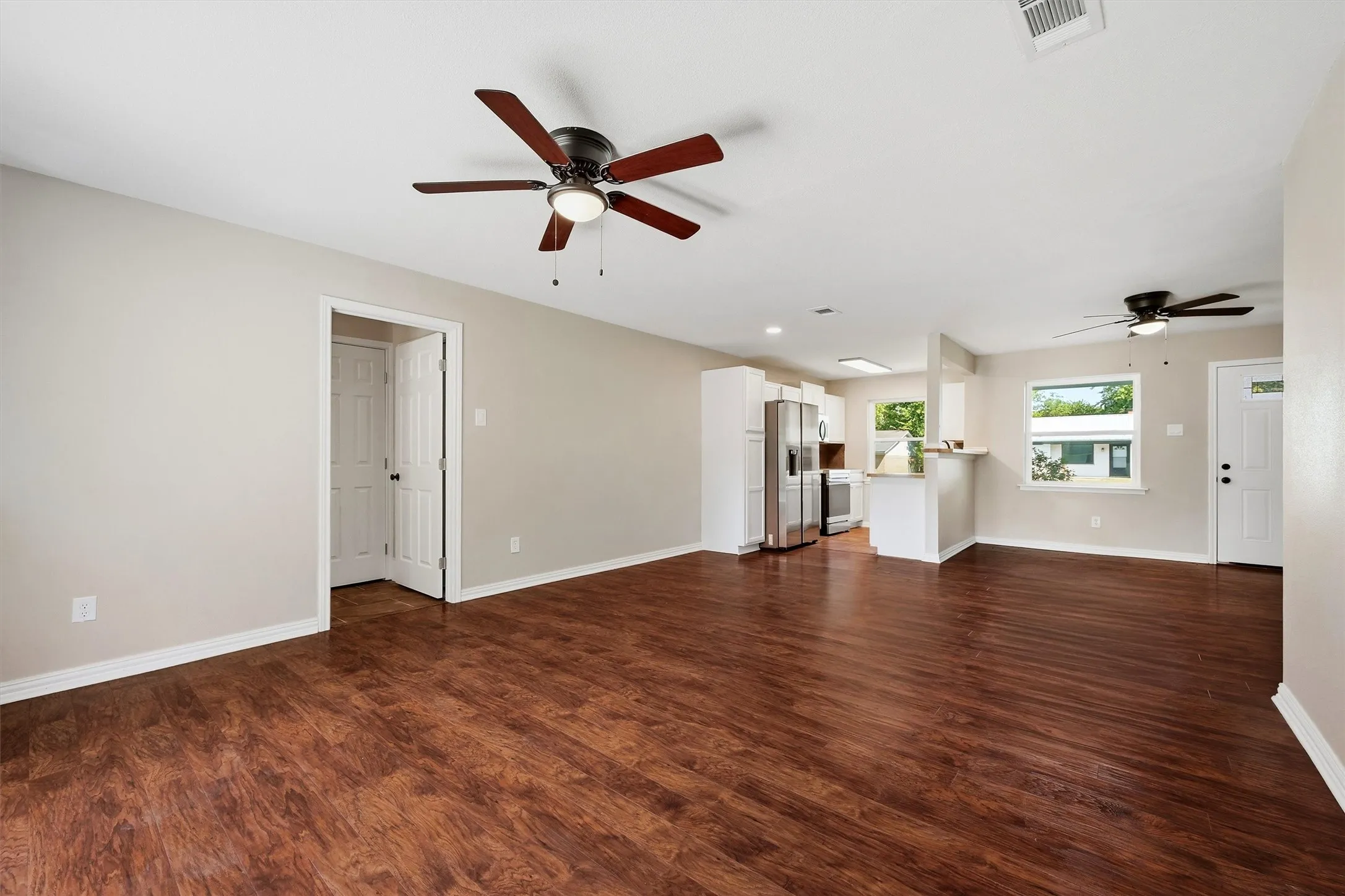 Wood-finish flooring, light neutral wall color, and multiple ceiling fans
