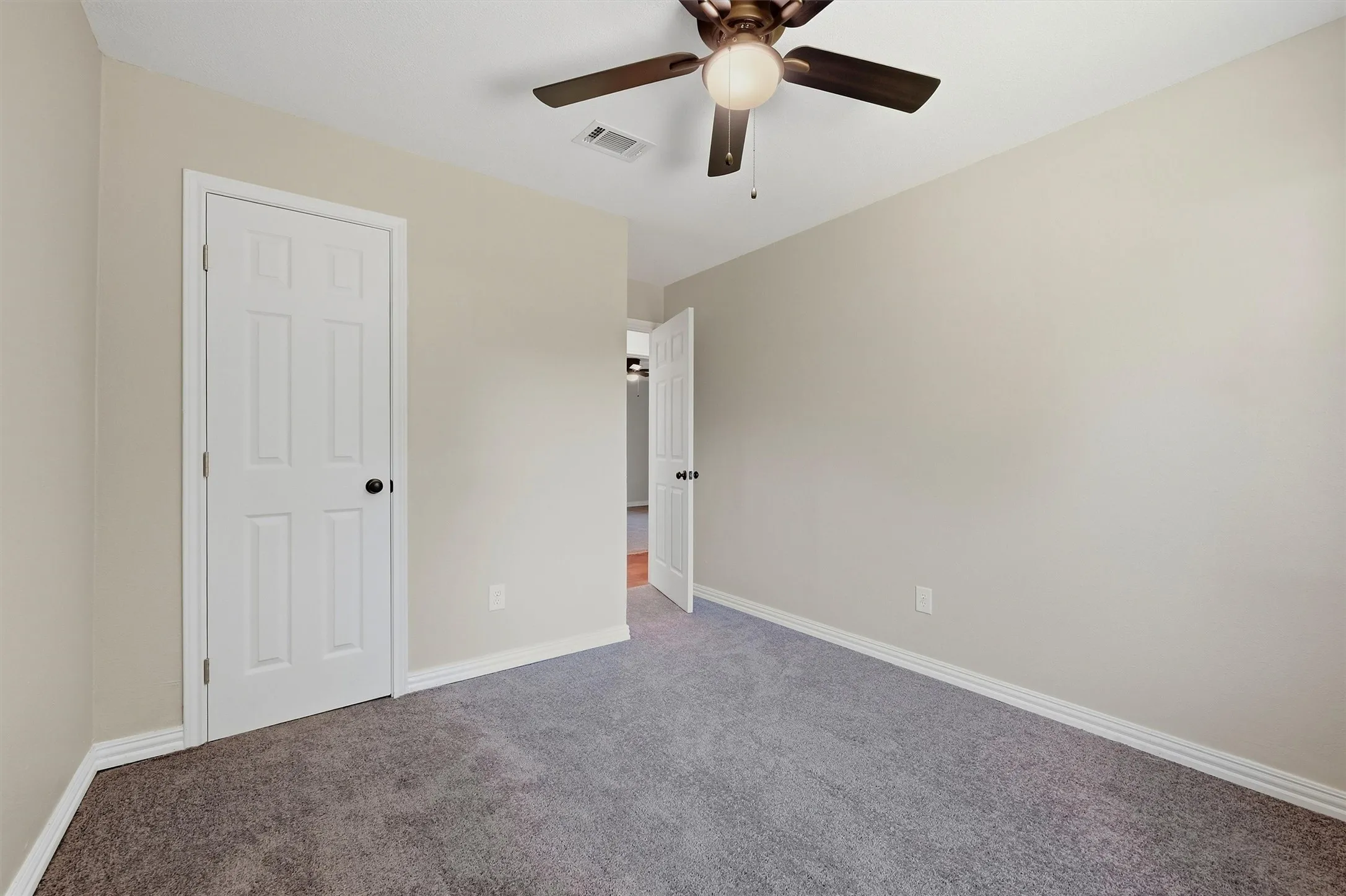 Neutral tone wall paint, gray carpet flooring, white trim, and a ceiling fan with integrated lighting