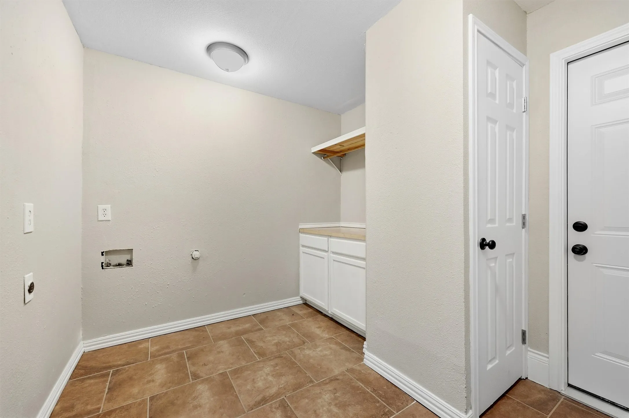 Tile flooring, white cabinetry, light countertop, wood shelving, and flush-mount ceiling lighting