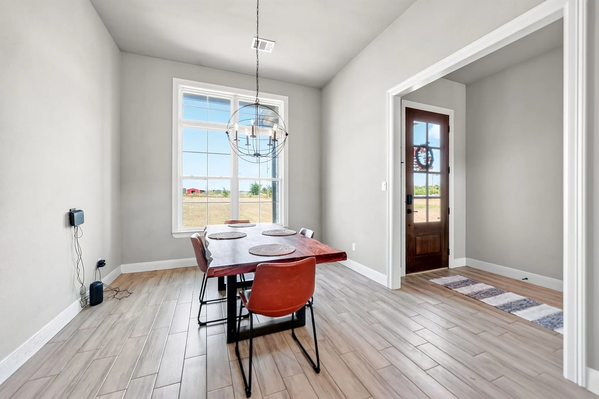 Recessed lighting, wood-finish flooring, white trim, prominent window, and dark wood-paneled door with glass inserts