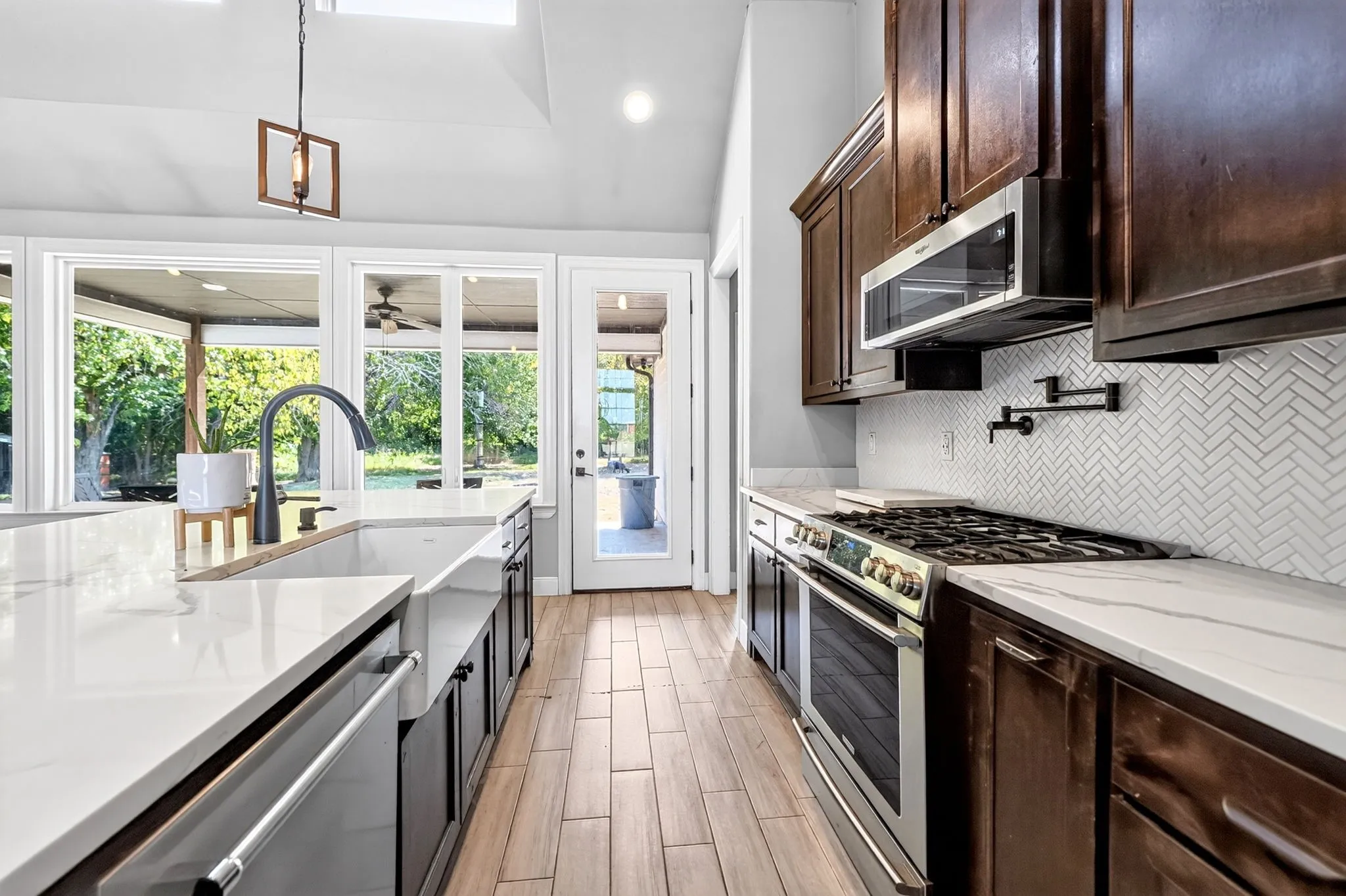 Kitchen featuring white countertops, dark wood-finish cabinetry, stainless steel appliances, a white herringbone tile backsplash, and wood-finish flooring