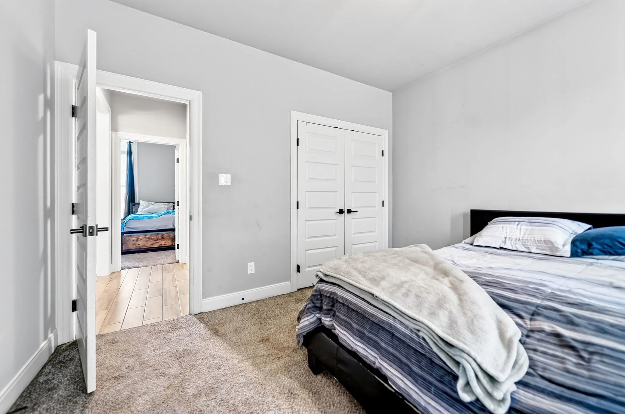 Light gray wall paint, white trim, white paneled doors with black hardware, and carpet flooring
