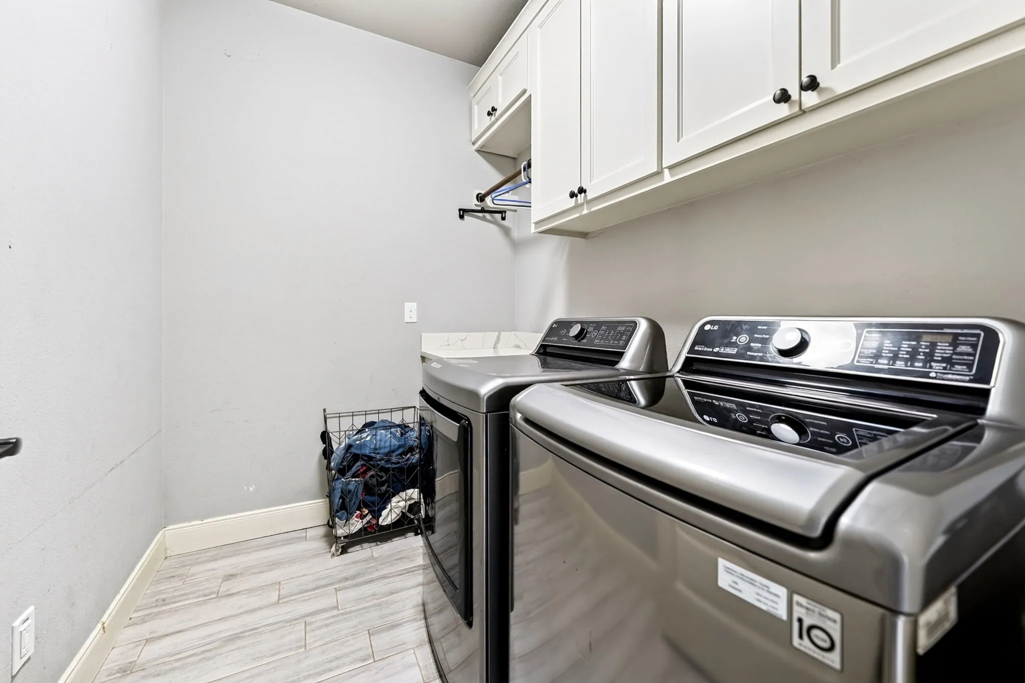 White shaker cabinetry, wood-finish flooring, and a countertop with a stone-look finish