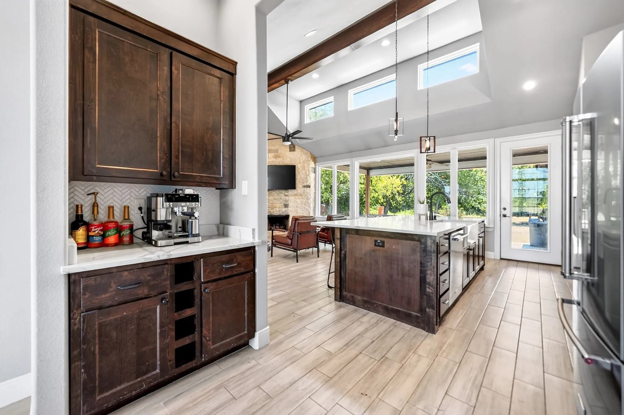 Spacious kitchen featuring a large central island, wood-finish flooring, and ample natural light from extensive windows