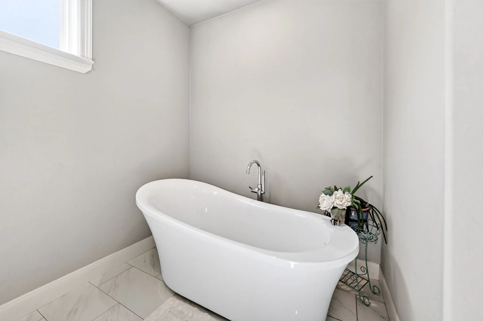 Freestanding soaking tub with a polished chrome floor-mounted faucet