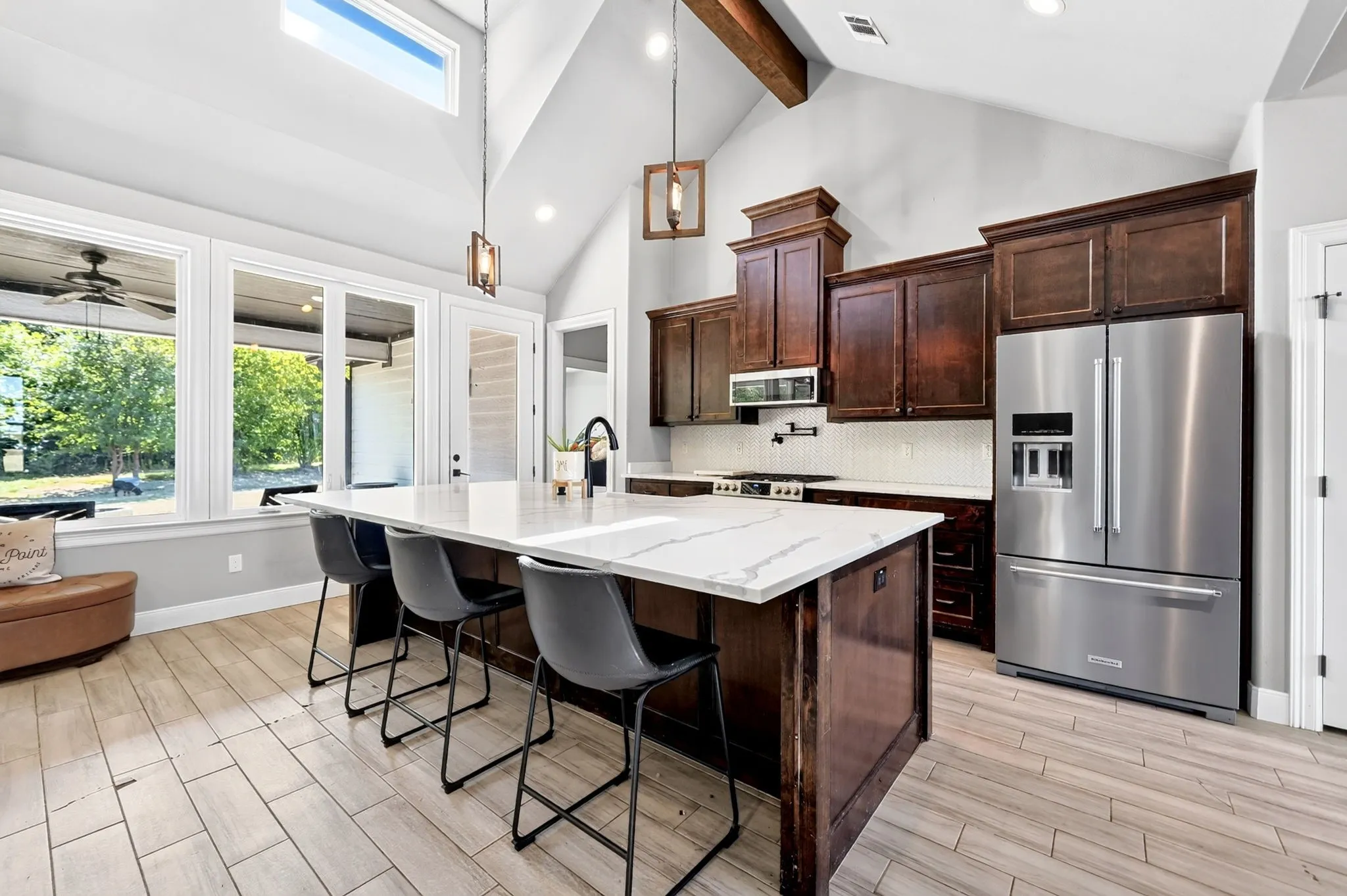Kitchen featuring wood-finish flooring, vaulted ceiling with exposed beam, and a large island with a light-toned countertop