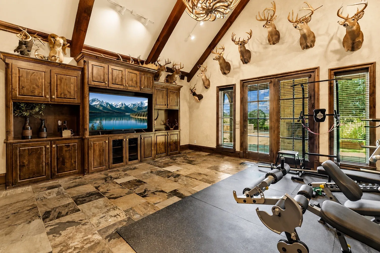amily room featuring a vaulted ceiling with beautiful accent beams, slate flooring, and French doors opening to a spacious patio with a wood-burning fireplace—creating a warm and inviting space for relaxing and entertaining.