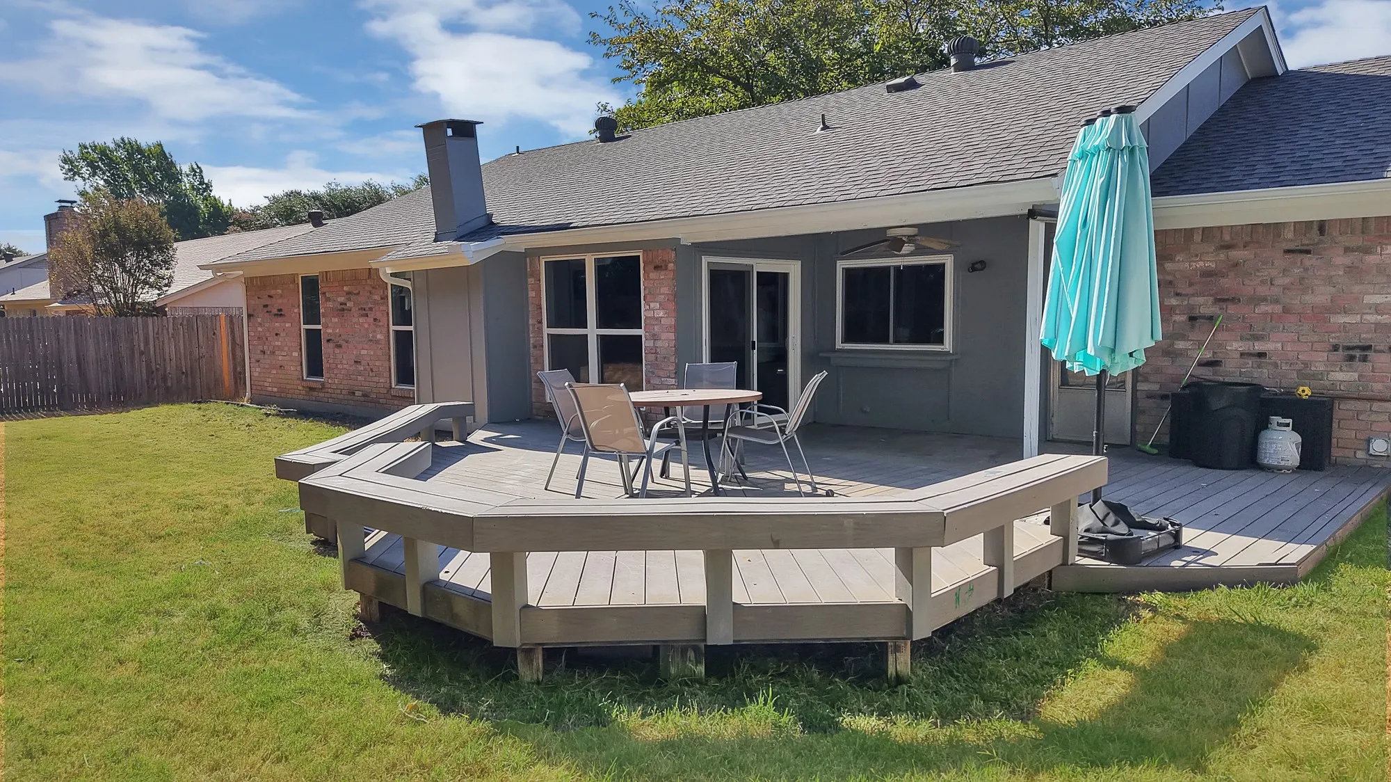 Expansive backyard featuring a multi-level composite deck with built-in seating, brick and stucco exterior, and a shingled roof