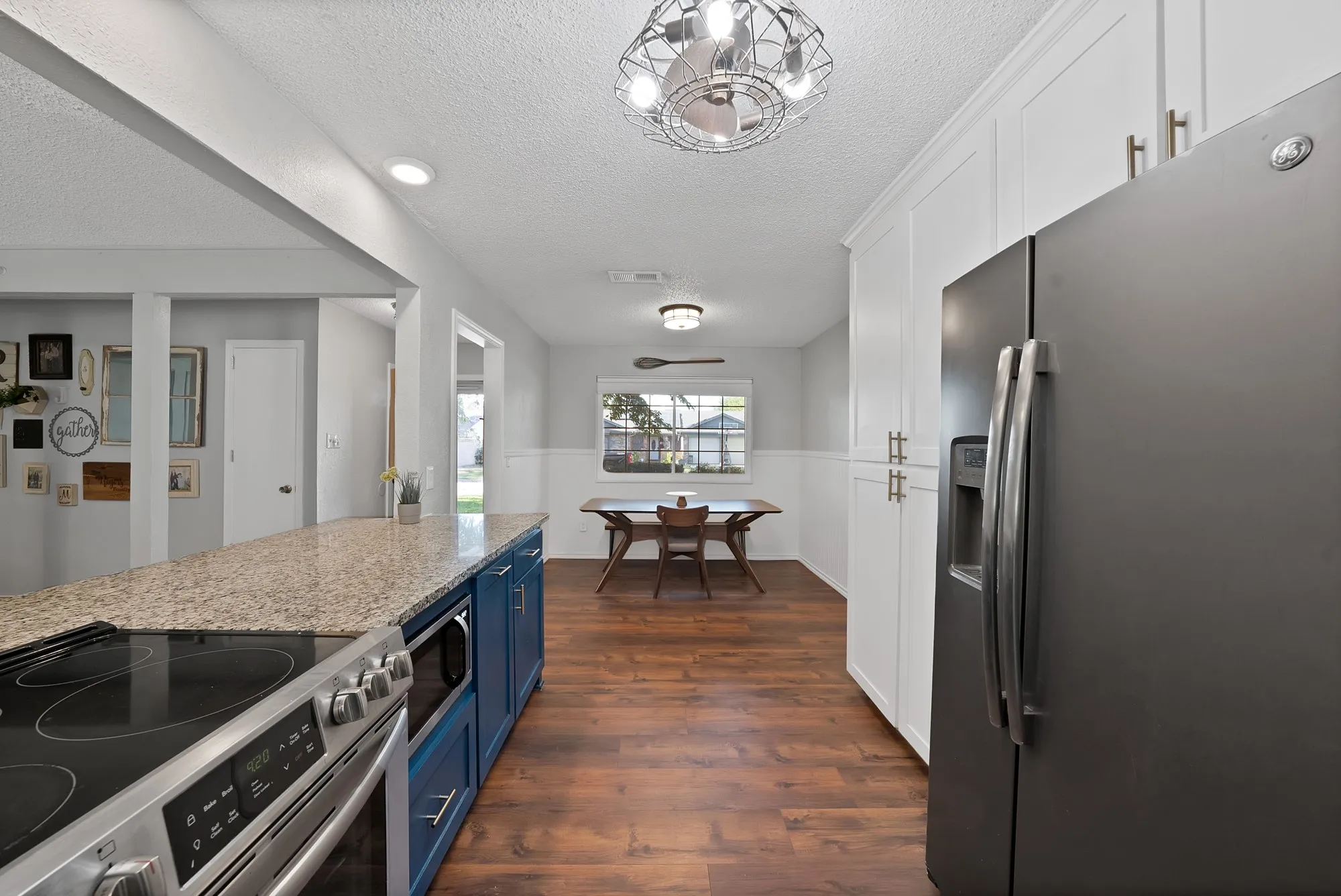 Kitchen featuring a built-in stainless steel oven, blue cabinetry with a light-colored countertop, and a built-in microwave