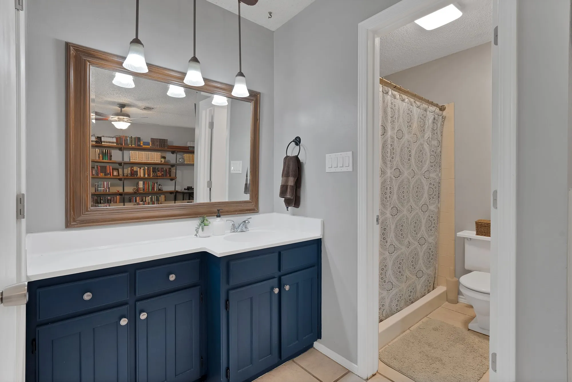 Dual-sink vanity with blue cabinetry, white countertop, and framed mirror