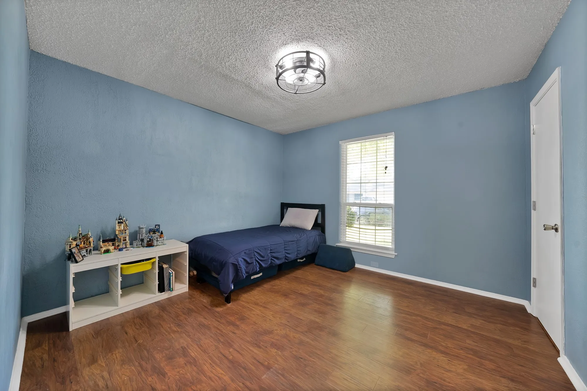 Room with wood-finish flooring, a window with blinds, and a ceiling-mounted light fixture