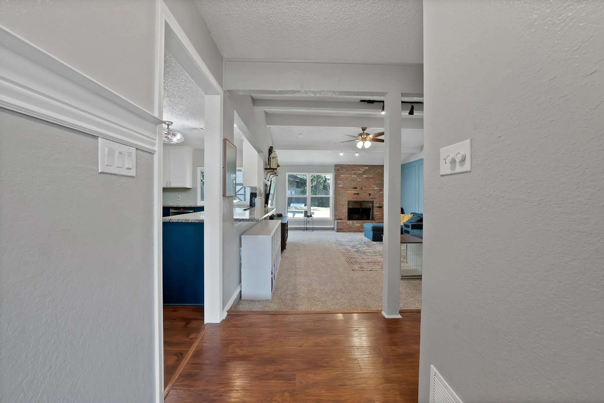 Wood-finish flooring, recessed lighting, exposed brick fireplace, and a ceiling fan with integrated lighting