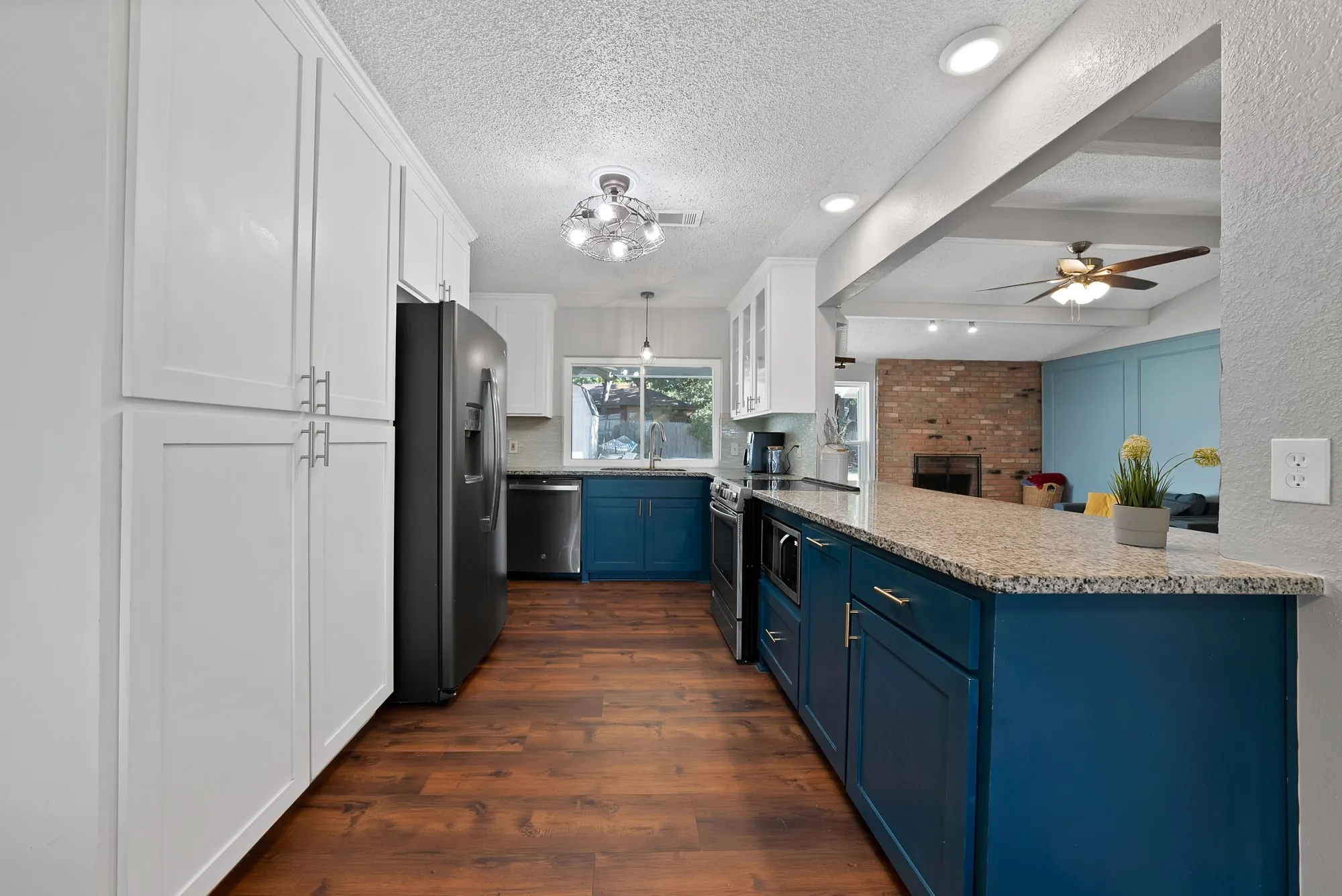 Kitchen featuring wood-finish flooring, white upper cabinetry, blue lower cabinetry, and light-colored countertops