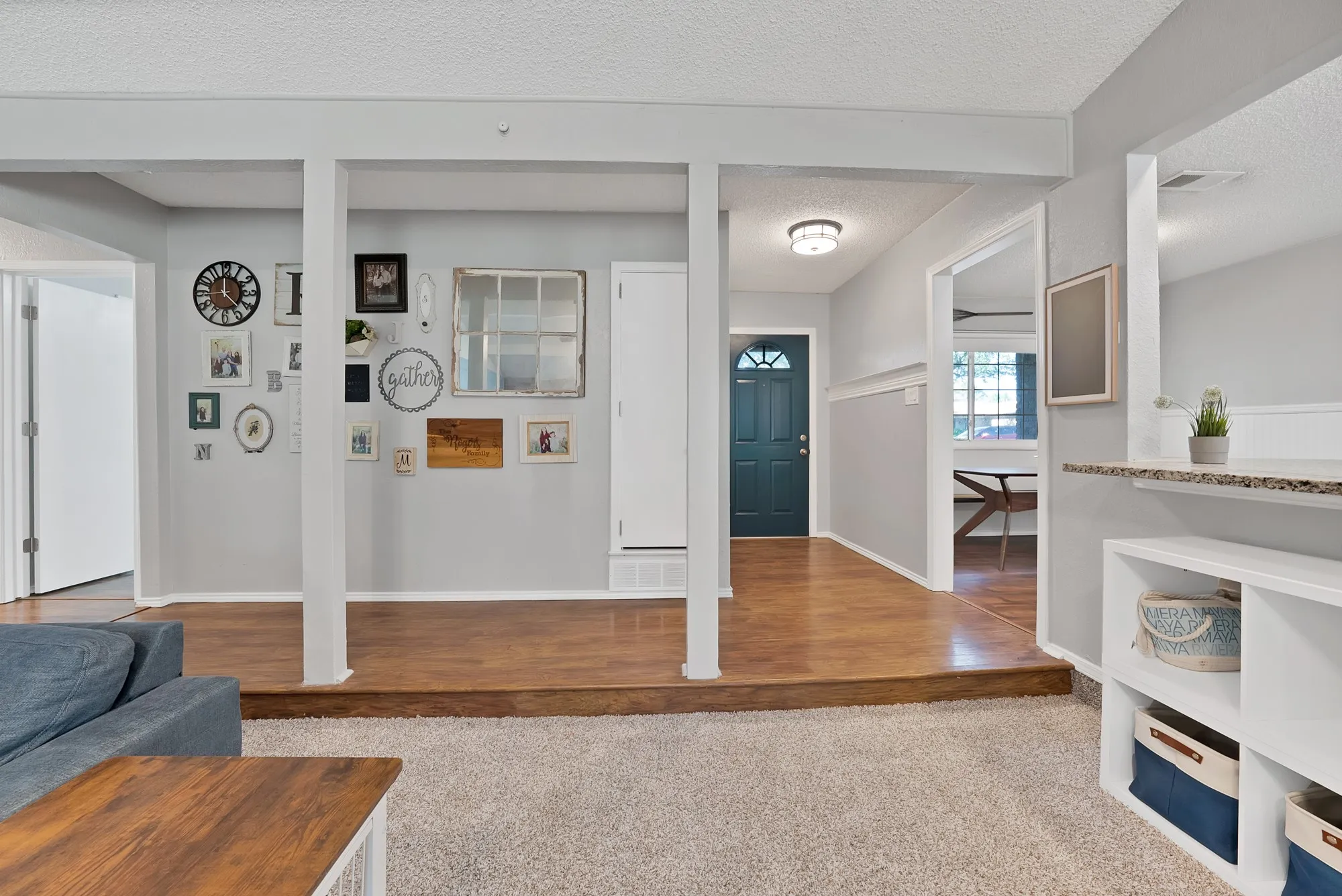 Raised wood-finish flooring, built-in shelving, recessed lighting, and a dark-paneled door
