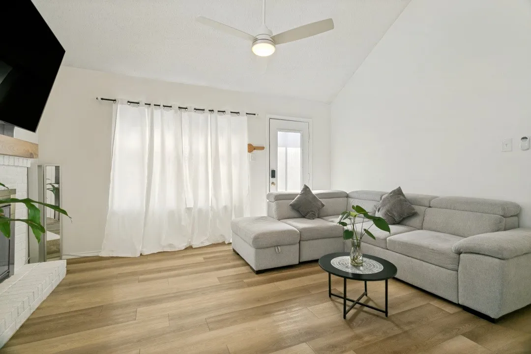 Living room with ceiling fan with notable chandelier, dark hardwood / wood-style floors, and a wealth of natural light
