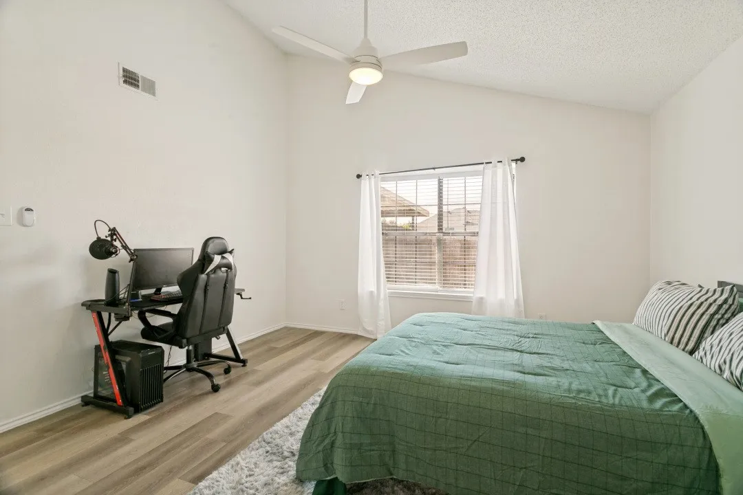 Master bedroom with wood-type flooring, connected bathroom, high vaulted ceiling, and ceiling fan