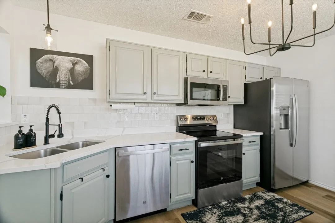 Kitchen with  appliances with stainless steel finishes, a textured ceiling, dark hardwood / wood-style flooring, and a notable chandelier
